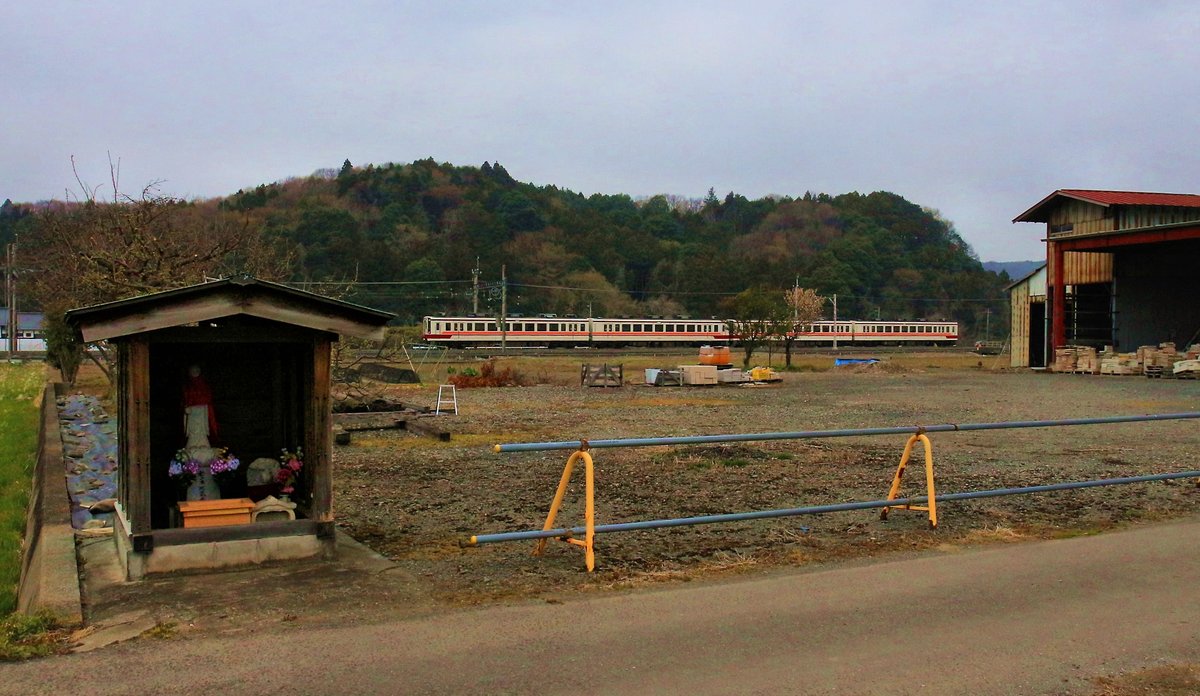 Zwei Regionalzüge Serie 6050 des Tôbu-Konzerns im bäuerlichen Japan bei Kita Kanuma; im Vordergrund ein typischer kleiner Schrein mit der Jizô-Gottheit, die Menschen und vor allem Kinder auf den richtigen Weg hilft. 30.März 2019 