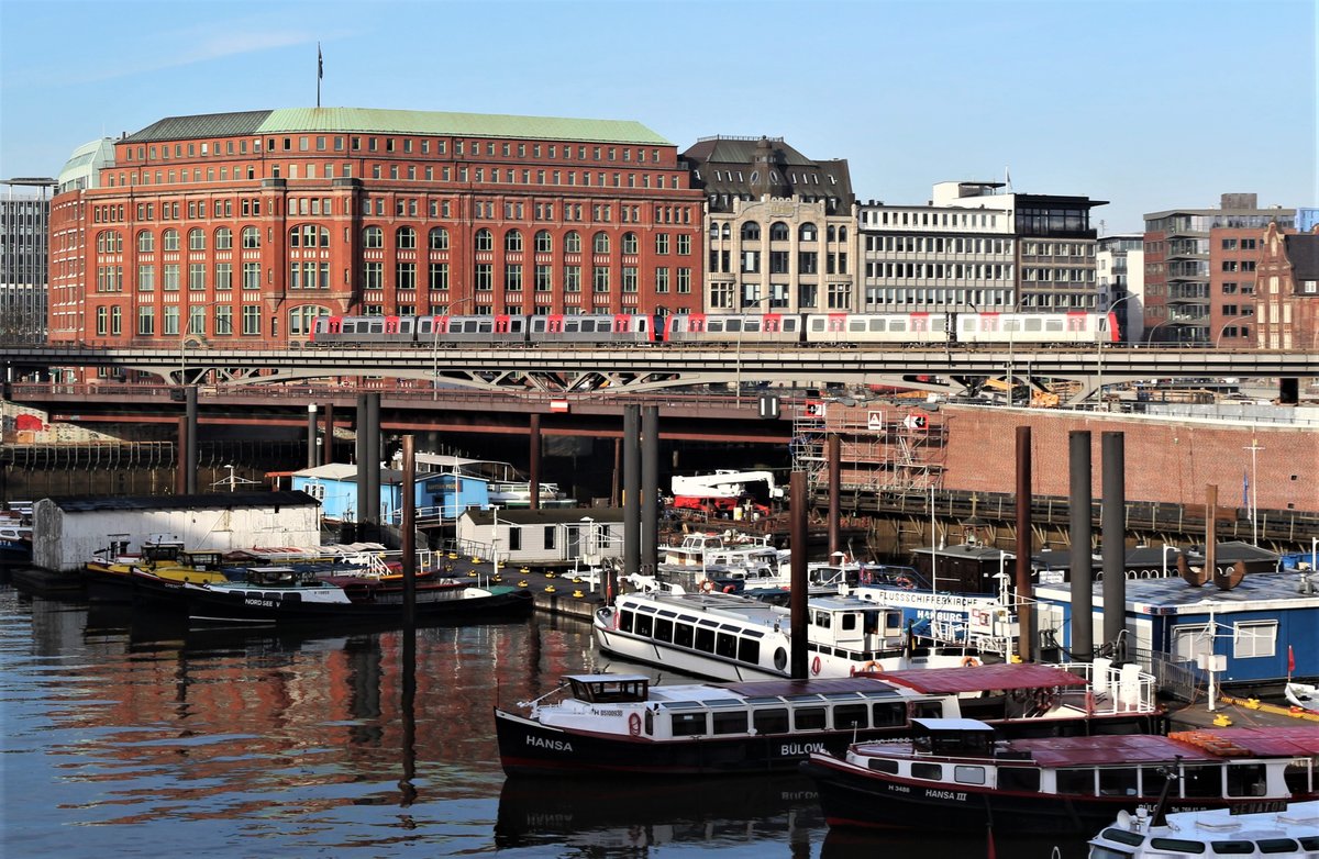 Zwei Triebzüge der Bauart DT5 der Hamburger Hochbahn (HHA) sind am 17. Februar 2018 auf der Hochbahnstrecke zwischen den Stationen Baumwall und Rödingsmarkt unterwegs zum nächsten Halt Baumwall als U3. Im Hintergrund das Überseehaus.