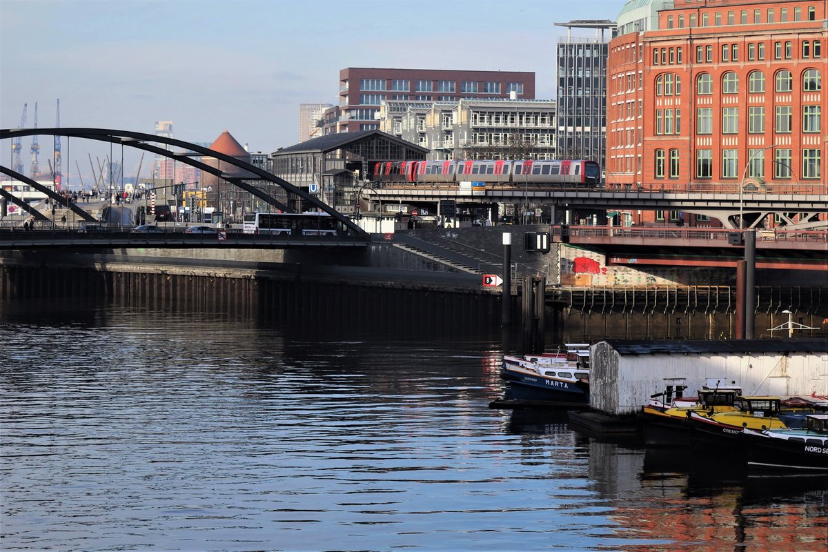 Zwei Triebzüge der Bauart DT5 der Hamburger Hochbahn (HHA) erreichen am 17. Februar 2018 auf der Hochbahnstrecke die Station Baumwall. Im Hintergrund das Überseehaus und die Station Baumwall (Elbphilharmonie).
