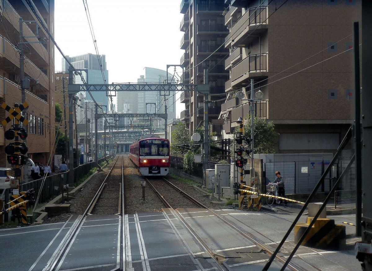 Zweiglinien des Keikyû-Konzerns - die Daishi-Linie: Zug 1501 (Serie 1500) bei Minato-chô in der dicht bebauten Stadt Kawasaki (an Tokyo anschliessend); im Hintergrund das Stadtzentrum mit seinen Hochhäusern. 24.Oktober 2011.  