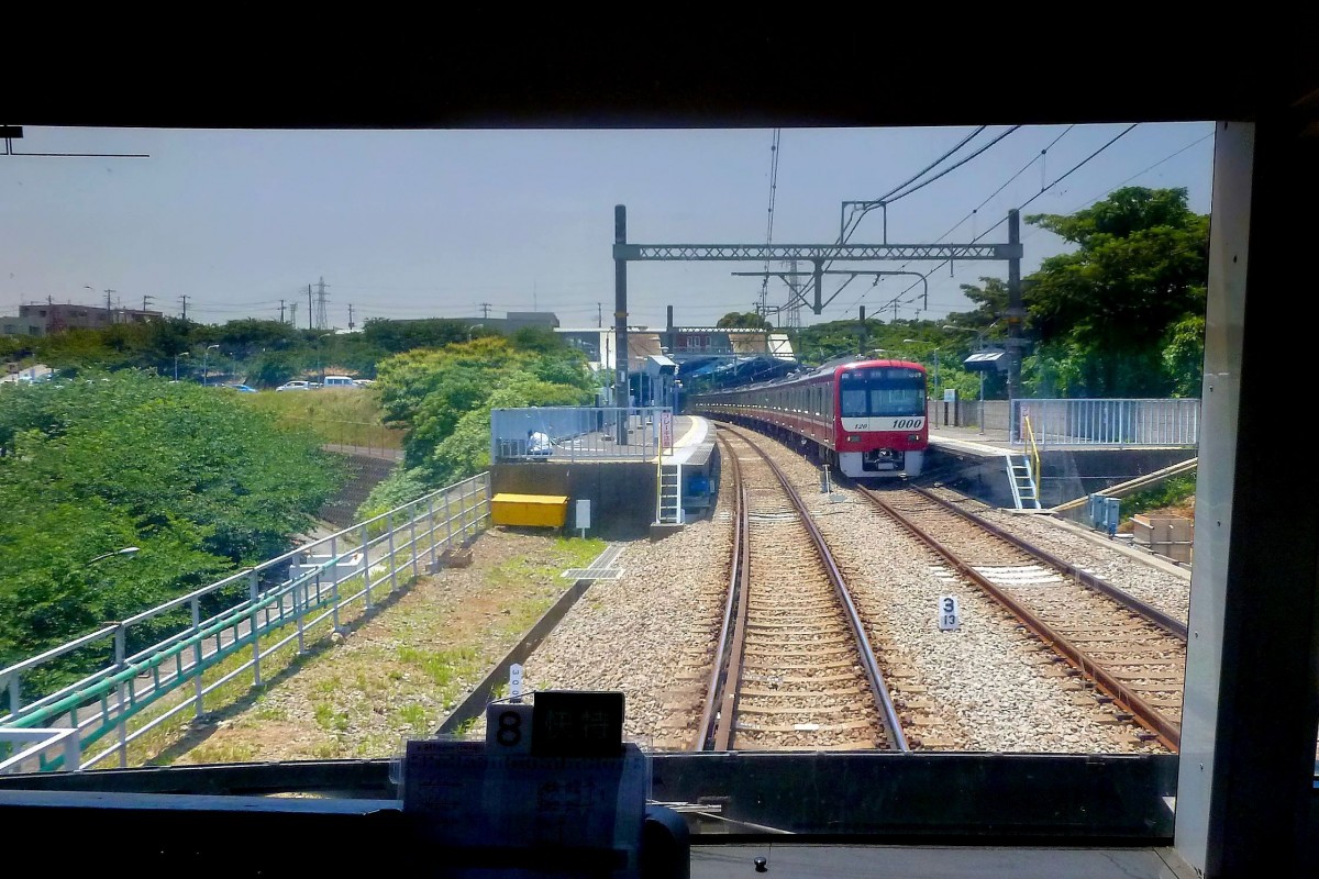 Zweiglinien des Keikyû-Konzerns - die Misakiguchi-Linie (13,4km): Diese Linie gelangt fast bis zur Südwestspitze der Miura-Halbinsel und erreichte 1975 den provisorischen Endbahnhof Misakiguchi (im Bild, mit Zug 1113 (Serie 1000)). Der Weiterbau ist allerdings fraglich, da es starken Protest seitens des Umweltschutzes gibt angesichts des prachtvollen Küstenwalds in dieser Gegend. 25.Juni 2011. (durchs verglaste Rückfenster des Führerstands eines einfahrenden Zugs) 