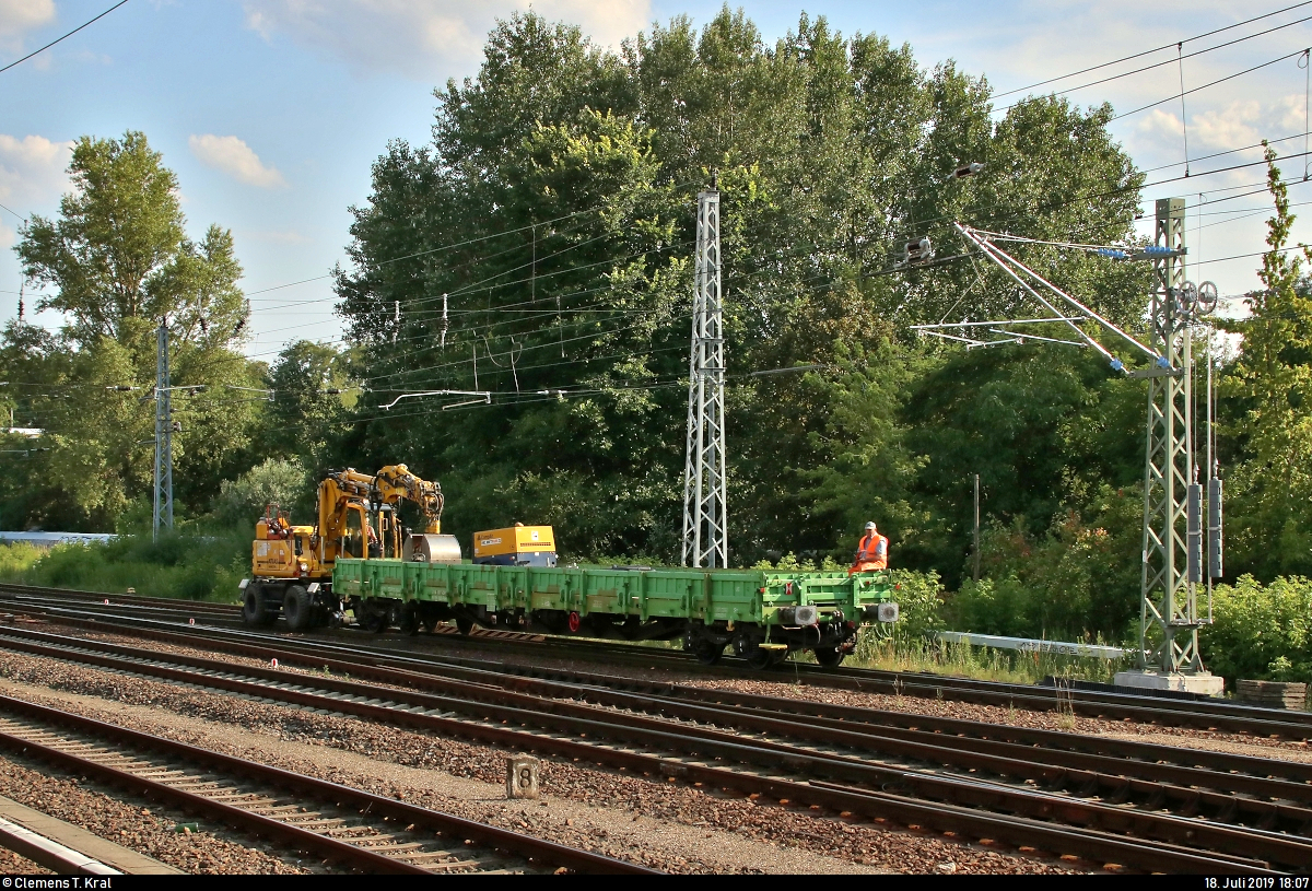 Zweiwegebagger ATLAS 1604 KZW (NVR-Nummer nicht bekannt) durchfährt, mit einem Flachwagen der Gattung  Res  (31 56 3937 429-9 SK-BUG) der BUG Verkehrsbau AG voran, den Bahnhof Berlin Springpfuhl auf dem Berliner Außenring (BAR | 6012) in nördlicher Richtung. Man beachte den Bauarbeiter an der Spitze.
Aufgenommen vom S-Bahnsteig (Gleis 20/21).
[18.7.2019 | 18:07 Uhr]