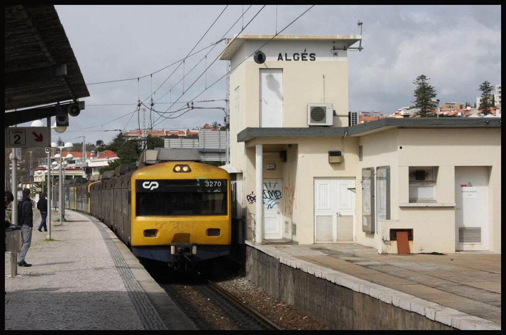 Zwischen dem Bahnhof Lissabon Cais do Sodre und dem ca. 50 km entfernten Küstenort Cascais an der Tejo Mündung verkehren S-Bahn Triebzüge auf einer zweigleisigen elektrifizierten Strecke. Cais do Sodre und Cascais sind die Endbahnhöfe und somit die Kopfbahnhöfe der Gesamtstrecke. Die Triebwagen der Reihe 32 bieten wegen der Breitspur Fahrzeuge fünf bequeme Sitzplätze in einer Reihe, drei rechts und zwei links vom Mittelgang! Die ET verkehren in ca. 20 Minuten Abstand und sind, wie hier am 20.3.2018, schon in der Vorsaison sehr gut ausgelastet. Hier fährt CP 3270 auf dem Weg nach Cais do Sodre in den Bahnhof Alges ein.