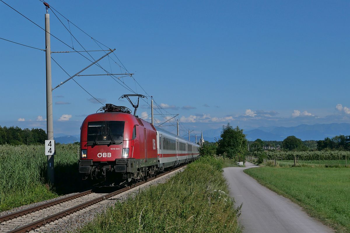 Zwischen Eriskirch und Friedrichshafen zieht 1016 041 nicht nur die Wagen des RJ 890, Bregenz - Lindau-Reutin und IC 890, Lindau-Reutin - Frankfurt (M) Hbf sondern auch die am Zugende abgebügelte 1116 271, dem nächsten Halt entgegen (11.07.2022)