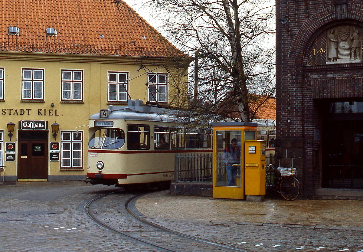 Zwischen Gasthaus und Kirche lag die Endhaltstelle Wellingdorf der Kieler Straßenbahn, hier mit Tw 267 am 27.04.1985. Telefonzelle und Briefkasten vervollständigen das 80er Jahre-Flair.