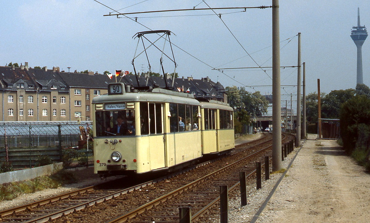 Zwischen der Gladbacher Straße und Düsseldorf-Hamm verläuft die Linie 708 auf eigenem Bahnkörper zwischen den Feldern, hier 1986 mit dem Verbandstriebwagen 379. Aus Anlaß des 90. Hafengeburtstages erhielten die historischen Fahrzeuge die Linienbezeichnung 90.