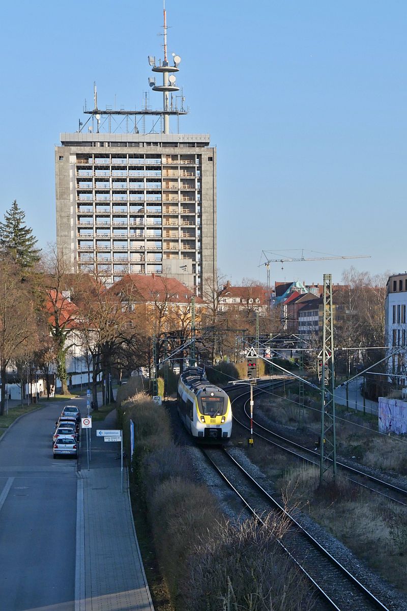 Zwischen Husern (|) - Zwischen dem entkernten Hochhaus und dem dahinterstehenden Kirchturm St. Gebhard auf der einen Seite und den Husern in Konstanz-Petershausen auf der anderen Seite, hat 3442 710 wenige Minuten zuvor die Fahrt als RE 4 / 4778 von Konstanz nach Stuttgart begonnen (27.02.2022)