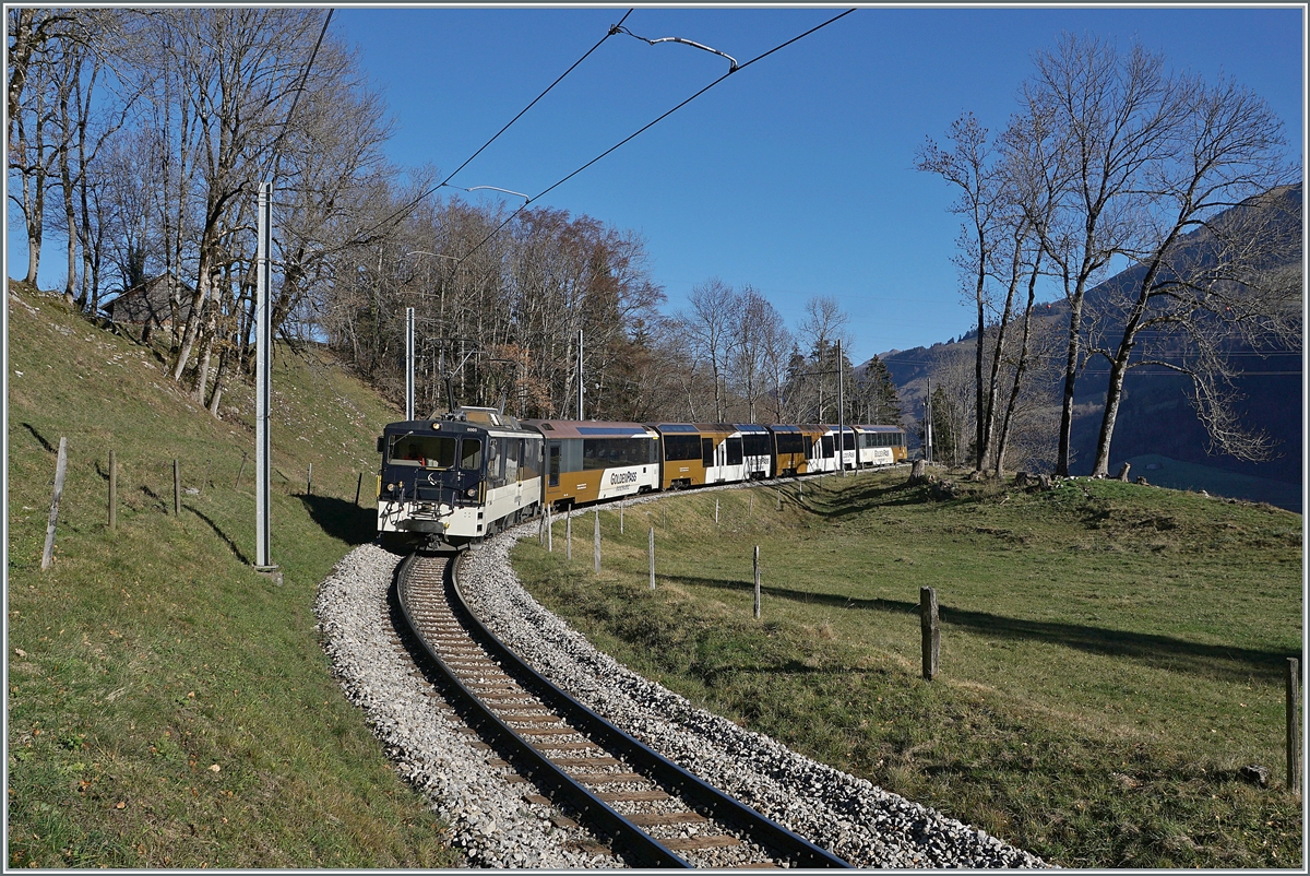 Zwischen Les Sciernes und Montbovon ist die MOPB GDe 4/4 6005 mit ihrem Zug nach Zweisimmen unterwegs; es handelt sich eigentlich um den  PE 2122  der eigentlich eine Stunde später hätte fahren sollen.

26. November 2020