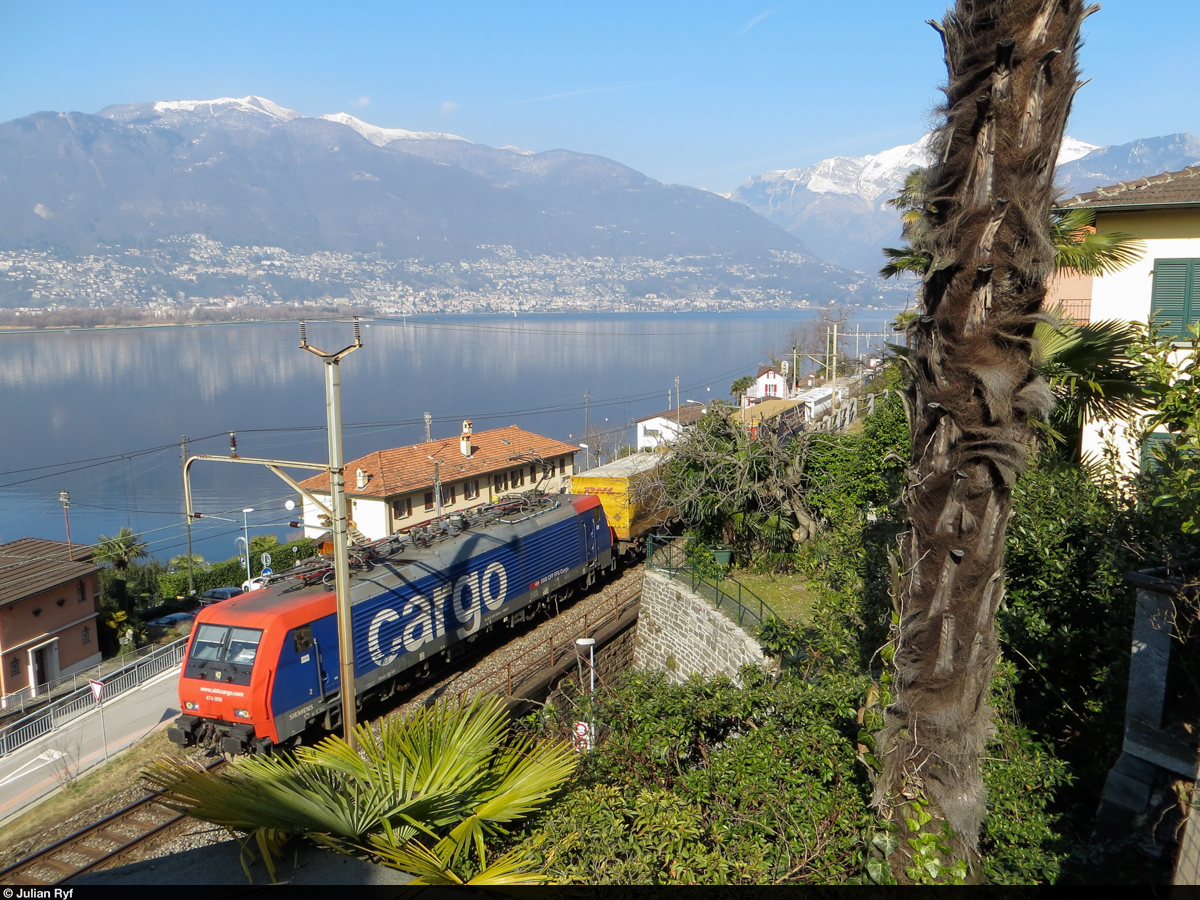 Zwischen Palmen hindurch zieht Re 474 009 am 2. März 2013 einen UKV-Zug in Richtung Italien. Aufgenommen in San Nazzaro am Lago Maggiore.