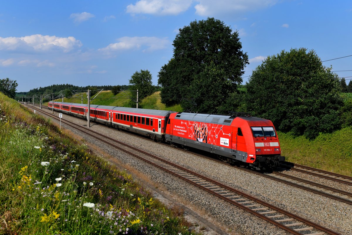 Zwischen Petershausen und Vierkirchen fuhr mir am 30. Juni 2018 der RE 4029 auf seiner Fahrt zum Münchner HBF vor die Linse. Geführt wurde der Zug von der 101 094, die mit ihrer Seitenwerbung darauf hinweist, dass die Mitarbeiter der Deutschen Bahn hart für jede Sekunde Pünktlichkeit arbeiten. 