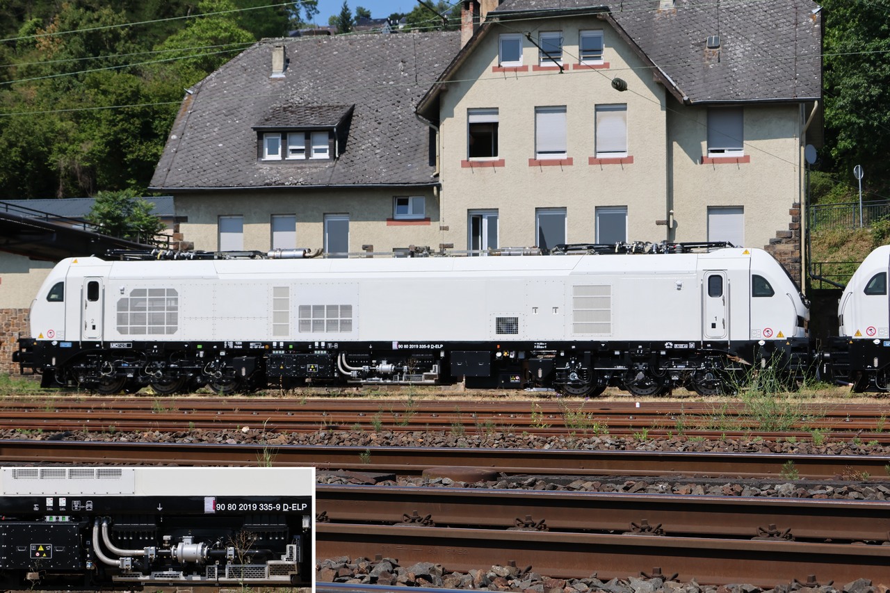 09.Juli 2026, 15:35 Uhr: Vor dem Geb�ude der Eifelbahn Verkehrs GmbH (Rheinh�ller 3) im ehemaligen BW-Linz reflektierten die offenbar flammneuen, 23m langen  Schwesterloks  Stadler 2019 335-9 (hier im Bild) und Stadler 2019 336-7  das grelle Sonnenlicht. -
Im unteren Bildteil als Detail vergr��ert dargestellt ein Teil des Lokkastens mit der Fahrzeugnummer.