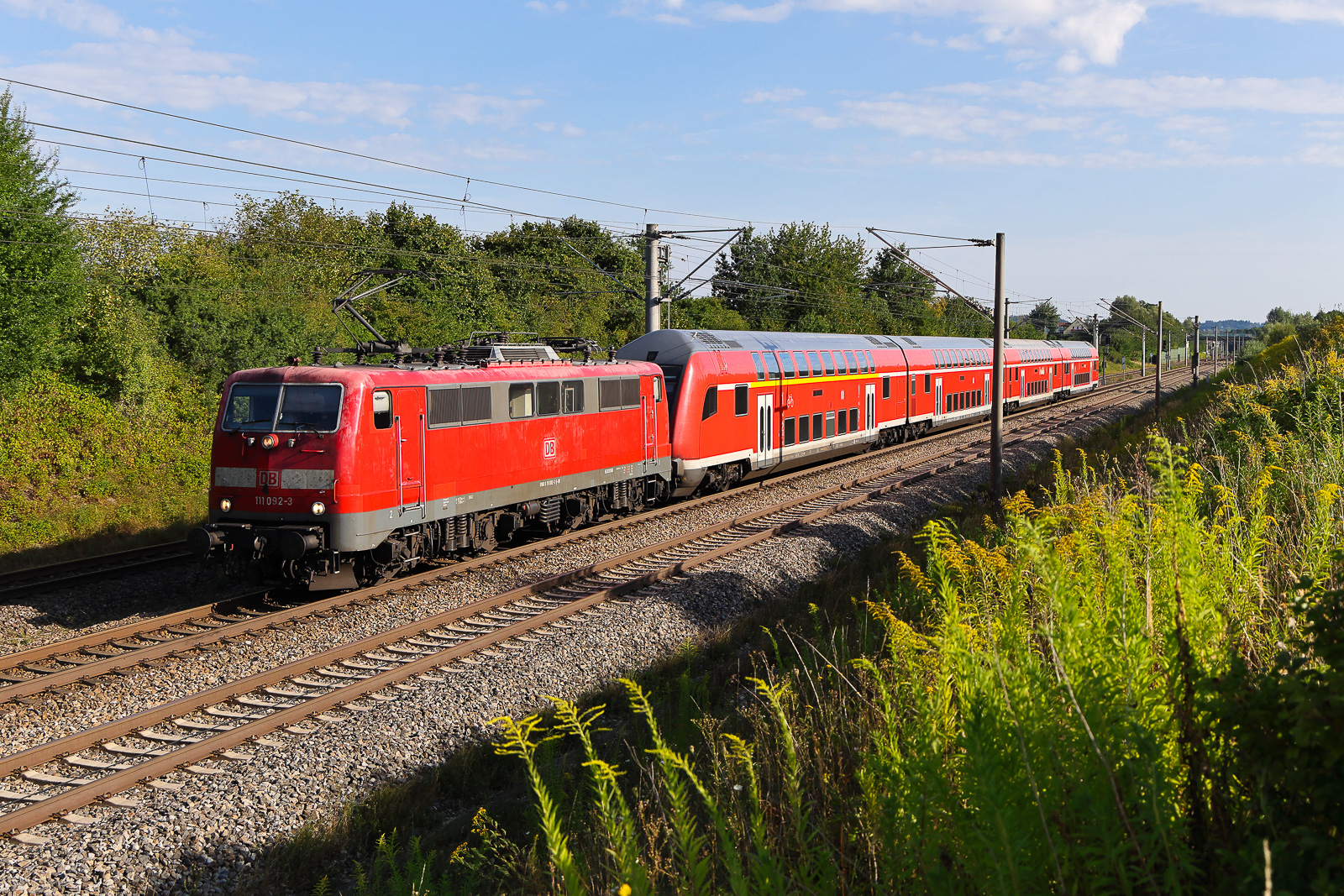 111 092 in der Früh am 11.08.2026 bei Vierkirchen. Die Lok zieht den Dosto in Richtung München.