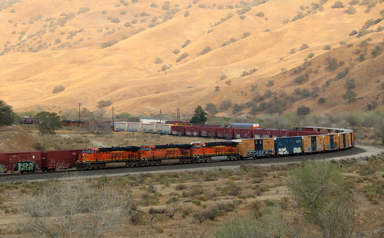 18.56 Uhr, kurz, nachdem die Sonne hinter den Bergen verschwunden ist: Der talwärts fahrende Güterzug ist im Schatten auf dem doppelspurigen Abschnitt angekommen. Caliente, CA, 26.9.2022