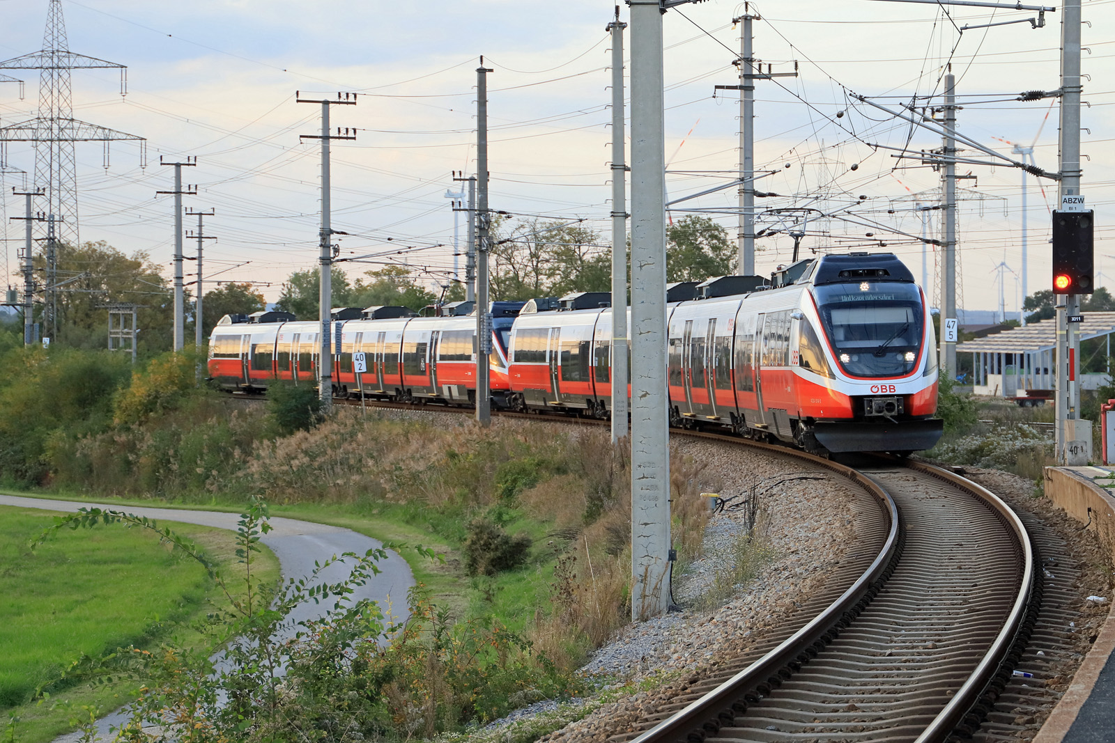 2 Triebzüge der Baureihe 4124 sind am 06.10.2022 gerade von der Ostbahn nach Süden abgebogen und werden gleich am Bahnsteig von Parndorf Ort zum Stehen kommen. Die beiden Fahrzeuge kommen so verbunden von Wien Hbf und werden im Bahnhof Neusiedl am See getrennt, die vordere Einheit fährt dann auf der Pannoniabahn weiter bis Wulkaprodersdorf, wo kurz vor Erreichen der GySEV-Stammstrecke auf das ungarische Stromsystem umgeschaltet werden muss. Dasselbe Los  trifft  den hinteren TALENT schon kurz nach der Ausfahrt aus Neusiedl am See, die Neusiedler Seebahn ist fast komplett mit 25 kV / 50 Hz überspannt, in diesem Fall hat die Bahn noch den langen Weg bis ins ungarische Fertőszentmiklós vor sich und etwas mehr als eine Stunde dafür benötigen.