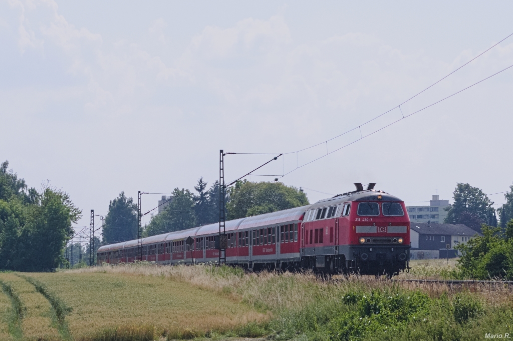 218 430, ehemals eine Lok der Erzgebirgsbahn, hatte über Jahre ihre Stammleistung am Zugpaar um RE27001, der von München über Mühldorf nach Simbach verkehrte. Hinter Markt Schwaben konnte am Nachmittag des 19.7.2013 die acht n-Wagen umfassende Regionalzugleistung aufgenommen werden.
