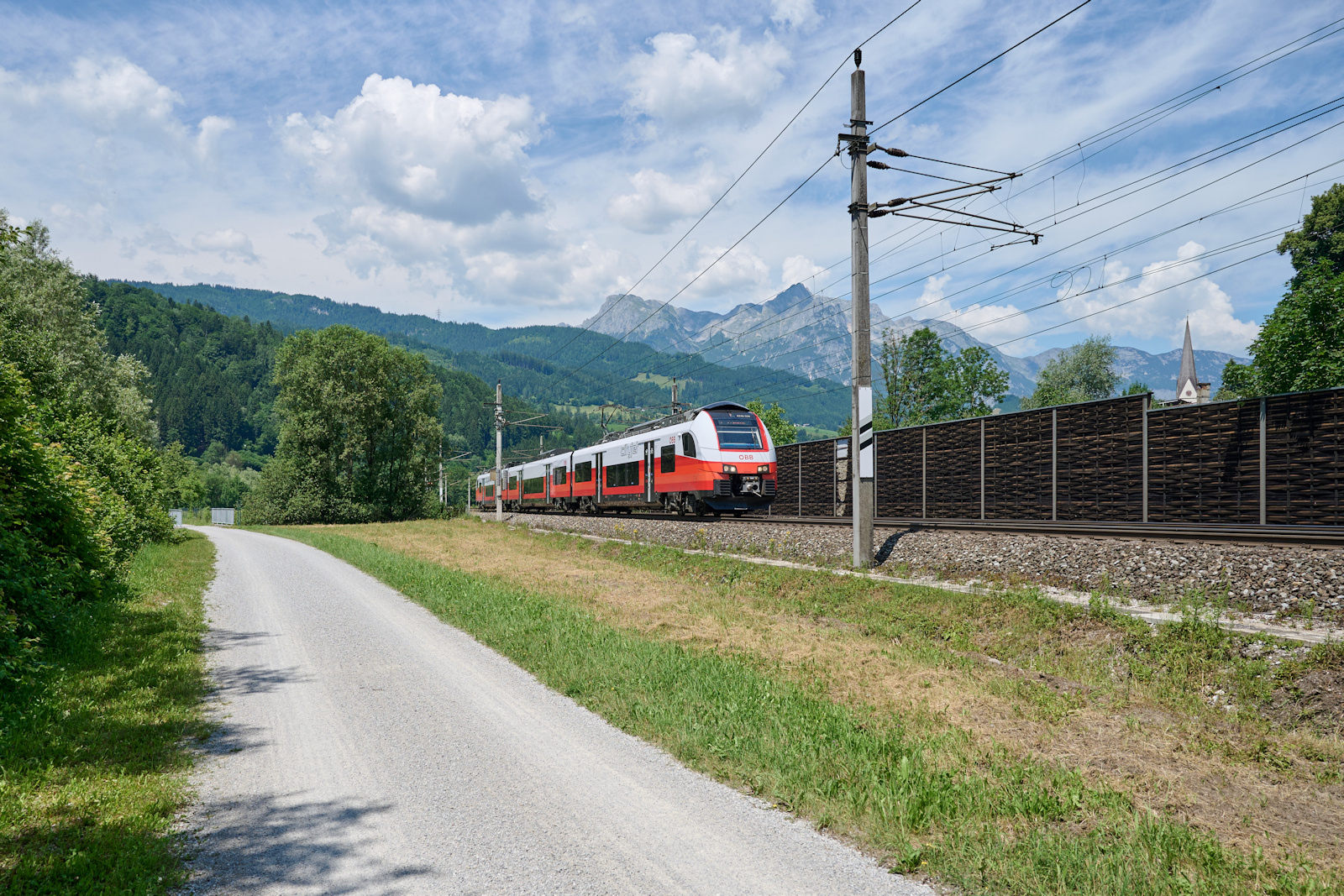 4746 036 war am 21.06.2026 als R 1512 auf dem Weg von Salzburg nach Saalfelden. Gerade hat der Zug Pfarrwerfen, welches mittlerweile hinter einer L�rmschutzwand versteckt wird, hinter sich gelassen. 