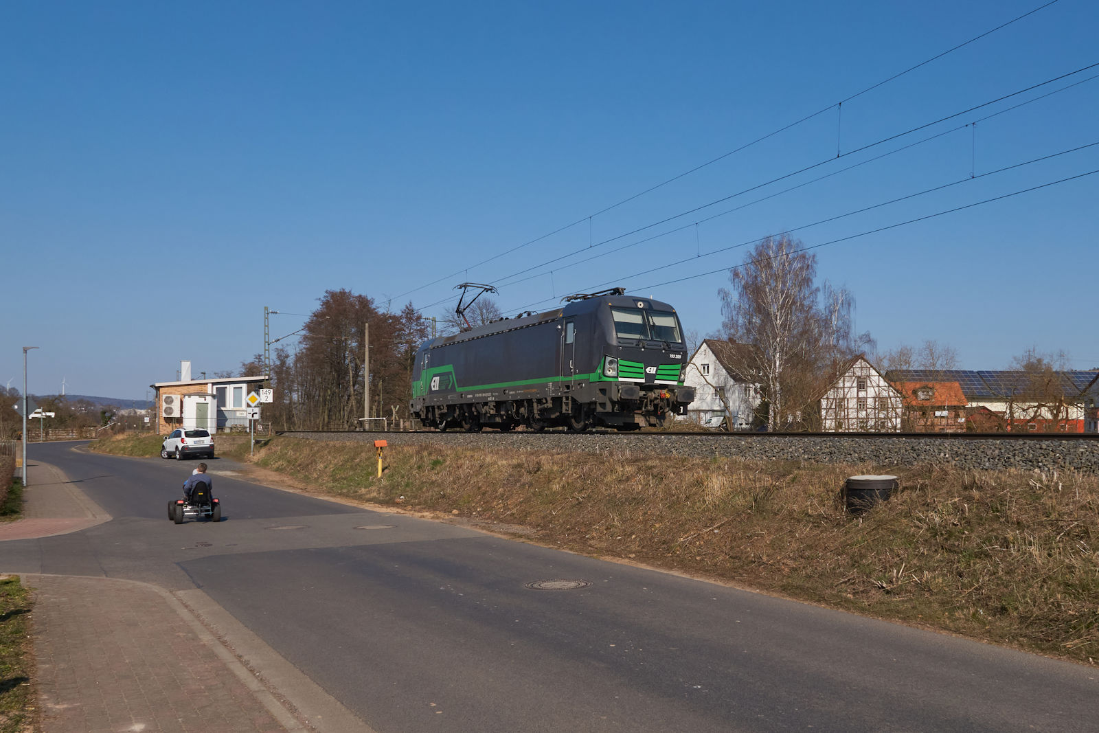 Am 13.03.2022 fuhr 193 209 der European Locomotive Leasing, welche an die Salzburg Eisenbahn Transport Logistik GmbH vermietet ist, allein durch Unterhaun in Richtung Fulda. Währenddessen genießen zwei Kinder den Sonntag auf Ihrem Tretauto.