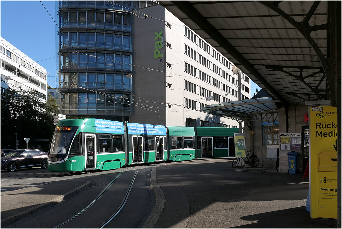 Am Basler Aeschenplatz  - 

Flixity 2 5029 auf der Linie 14 verschwindet an der Haltestelle Aeschenplatz hinter dem dortigen Kiosk. Um diesen herum führt eine Wendeschleife.

Die Blickrichtung entspricht in etwas der historischen Aufnahme von Frank Nowotny, nur bin ich näher am Kiosk. Die Bahnen der Linie 11 auf dem Bild von Frank haben an der dortigen Wendeschleife gedreht, die im Linksverkehr befahren wird.
https://www.bahnbilder.de/bild/schweiz~strassenbahn~strassenbahn-basel-bvb-blt-2/1417299/baseler-strassenbahn-mit-schweizer-standardwagen-und.html
Wie man sieht entstand an dieser Stelle ein Neubau.

18.09.2025 (M)