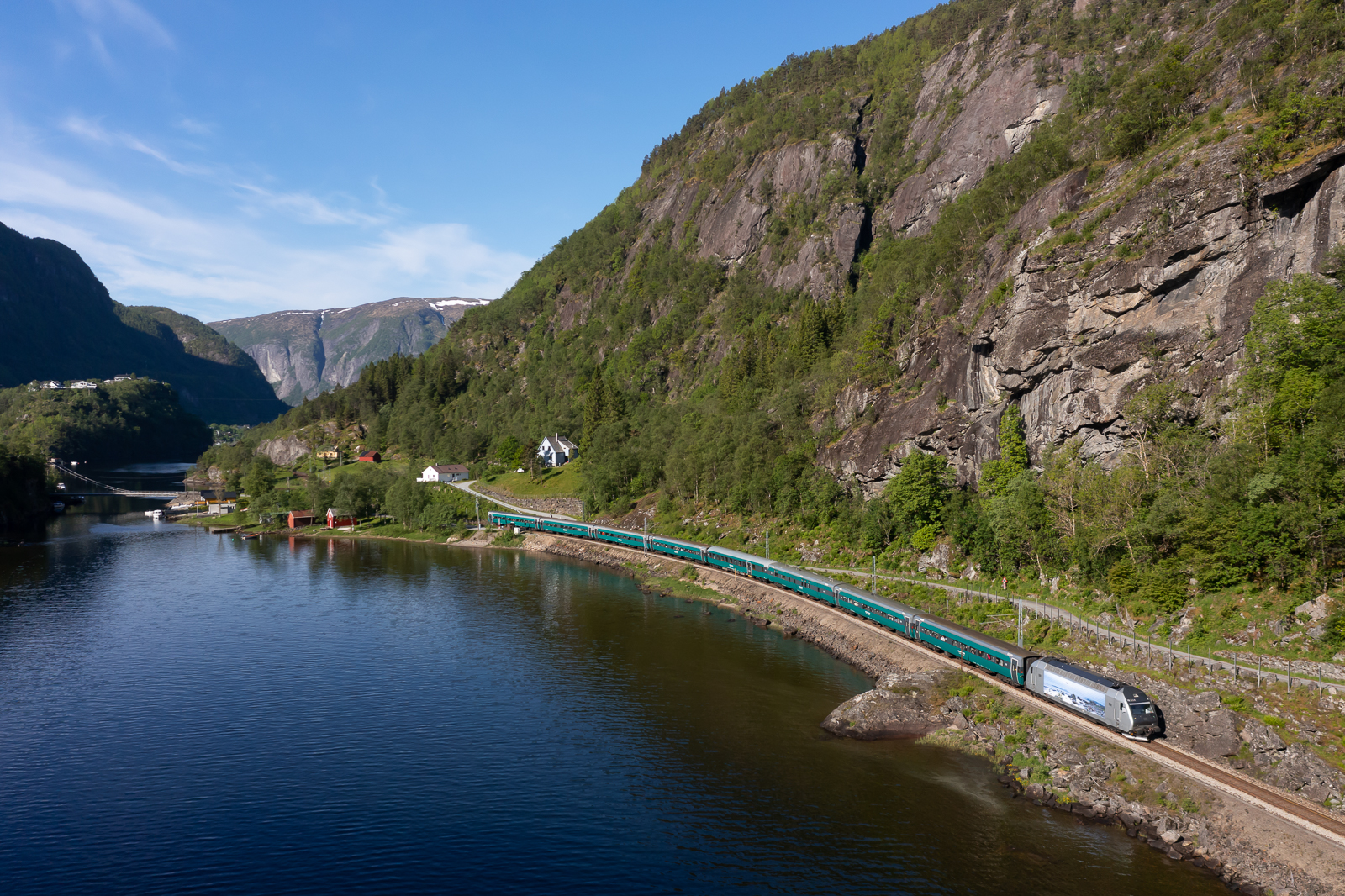 Am Morgen des 07.06.2022 zieht El 18 2254 ihren Reg 62 bei Stanghelle in Richtung Voss bzw. Oslo. Gut zu erkenen ist der ehemalige DB Wagen der Gattung BDcm. 2021 hat die Vy acht Liegewagen von der DB gekauft um sie auf der Bergenbahn einzusetzten. So können nun auch Fahrräder in den Zügen mitgenommen werden und in den beiden Nachtzügen zwischen Oslo und Bergen gibt es nun neben Schlaf- und Sitzwagen auch Liegewagen. 