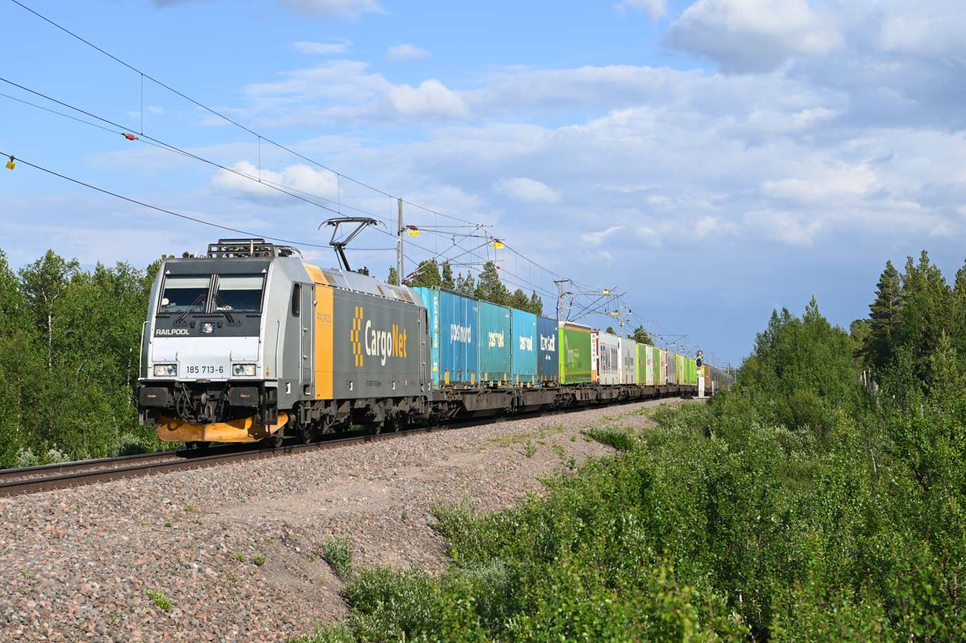 Am Nachmittag des 02.07.2022 zieht 185 713 ihren Arctic-Rail-Express nach Narvik. Hier ist der ARE zu sehen bei der Druchfahrt durch Rautas.