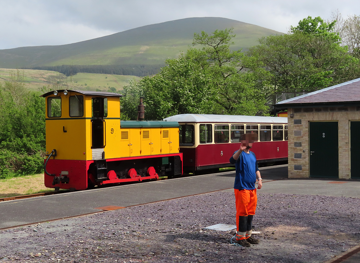 Auf einem Unterwegsbahnhof zwischen Caernarfon und Porthmadog grüsst dieser Bauarbeiter die Touristen im Dampfzug. Porthmadog, 14.5.2022