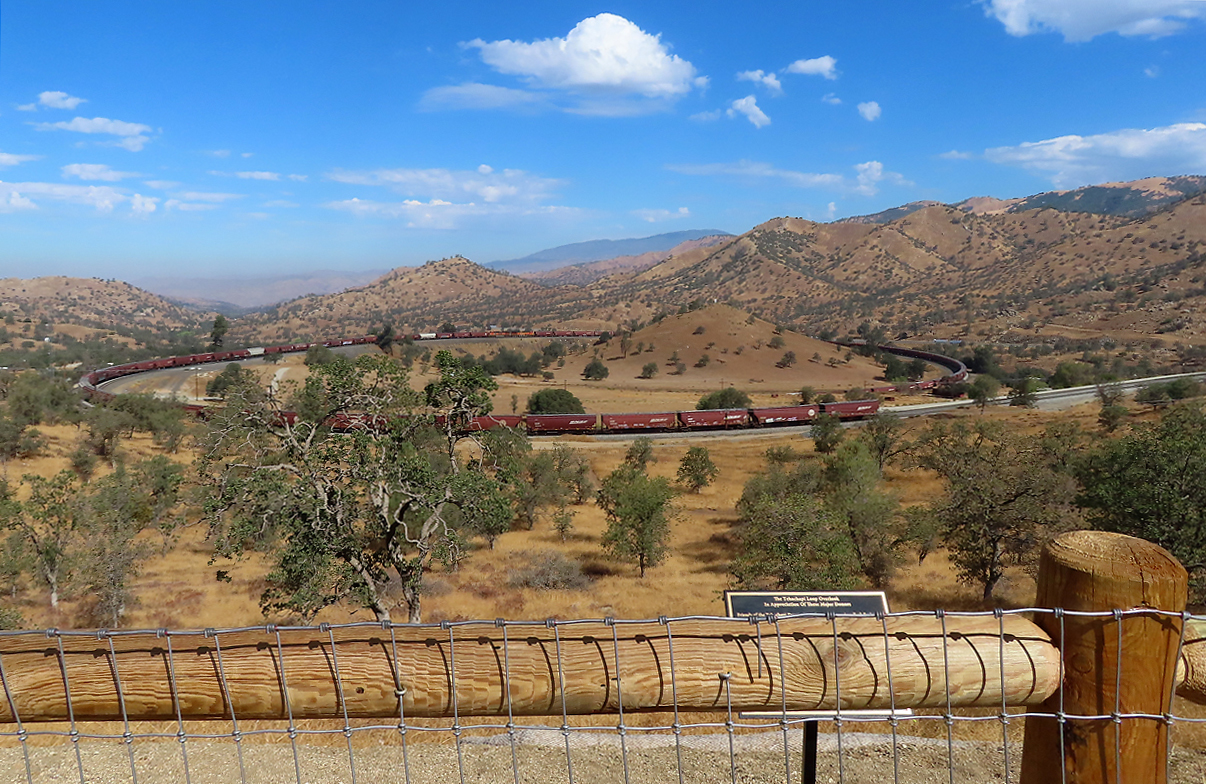Besucherplattform beim weltberühmten Tehachapi-Loop (direkt an der Landstrasse): die Sicht von hier aus ist ziemlich eingeschränkt. Die guten Fotostandpunkte befinden sich leider auf Privatgelände. Beim Anfang des Pfades, der zu den Fotostellen oberhalb des Loops führt, hat es ein Schild, welches das Betreten des Geländes verbietet. Gleich beim Ausgang talwärts des ‚Loop-Tunnels‘ (Tunnel 9) hat es eine Farm, auch dort ist das Betreten des Geländes verboten. Wir suchten den Besitzer der Farm auf, ein netter, älterer Herr. Er hatte riesige Freude an uns und wir plauderten über alles Mögliche. Er erlaubte uns dann das Betreten seines Grundstückes in den folgenden Tagen und sagte uns noch, welches Tor das Stabilste sei und deshalb bestens zum Übersteigen geeignet sei... Und zur Verbotstafel zum Pfad oberhalb des Loops meinte er, der Besitzer wohne weiter weg und an das Verbot würde sich sowieso niemand halten. So kamen wir zu sensationellen Fotos von dieser einmaligen Linienführung aus den verschiedensten Blickwinkeln, die ich aber gemäss den Richtlinien von Bahnbilder.de hier nicht veröffentliche. Es ist also hier wie an vielen anderen Orten auch: man muss reden mit Leuten! Fotografisch bietet aber die Linie vom Loop aus talwärts noch recht viele sehr gute Fotostellen. Es folgen Fotos davon… Tehachapi, CA, 27.9.2022
