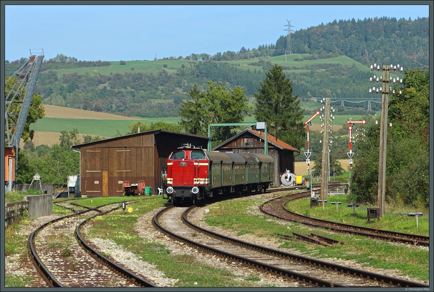 Betrieblicher Mittelpunkt der Sauschwänzlebahn ist der Bahnhof Fützen, hier befindet sich der Lokschuppen der Dampflokfreunde Schwarzwald-Baar, deren 50 2988 öfter auf der Strecke zum Einsatz kommt. Am 02.10.2023 zieht V80 BB ihren Zug aus 5 Umbauwagen an den Ausfahrsignalen vorbei in den Bahnhof. Im Hintergrund ist auch der Biesenbach-Viadukt zu sehen, den der Zug einige Minuten zuvor passiert hat.