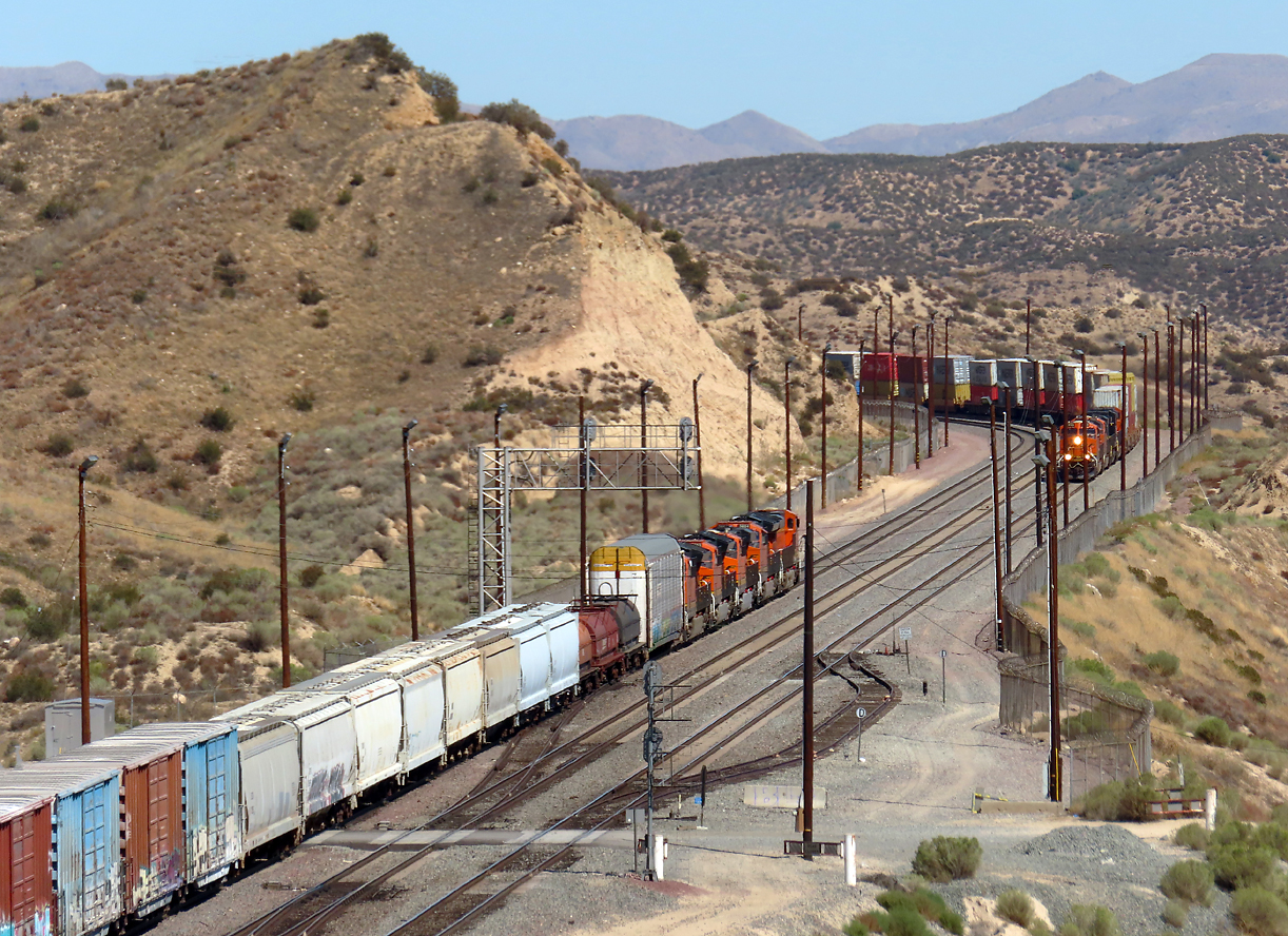 BNSF trifft BNSF auf der Passhöhe Cajon Pass: gemischter Güterzug begegnet Containerzug in der Nachmittagssonne. Cajon Pass, CA, 21.9.2022