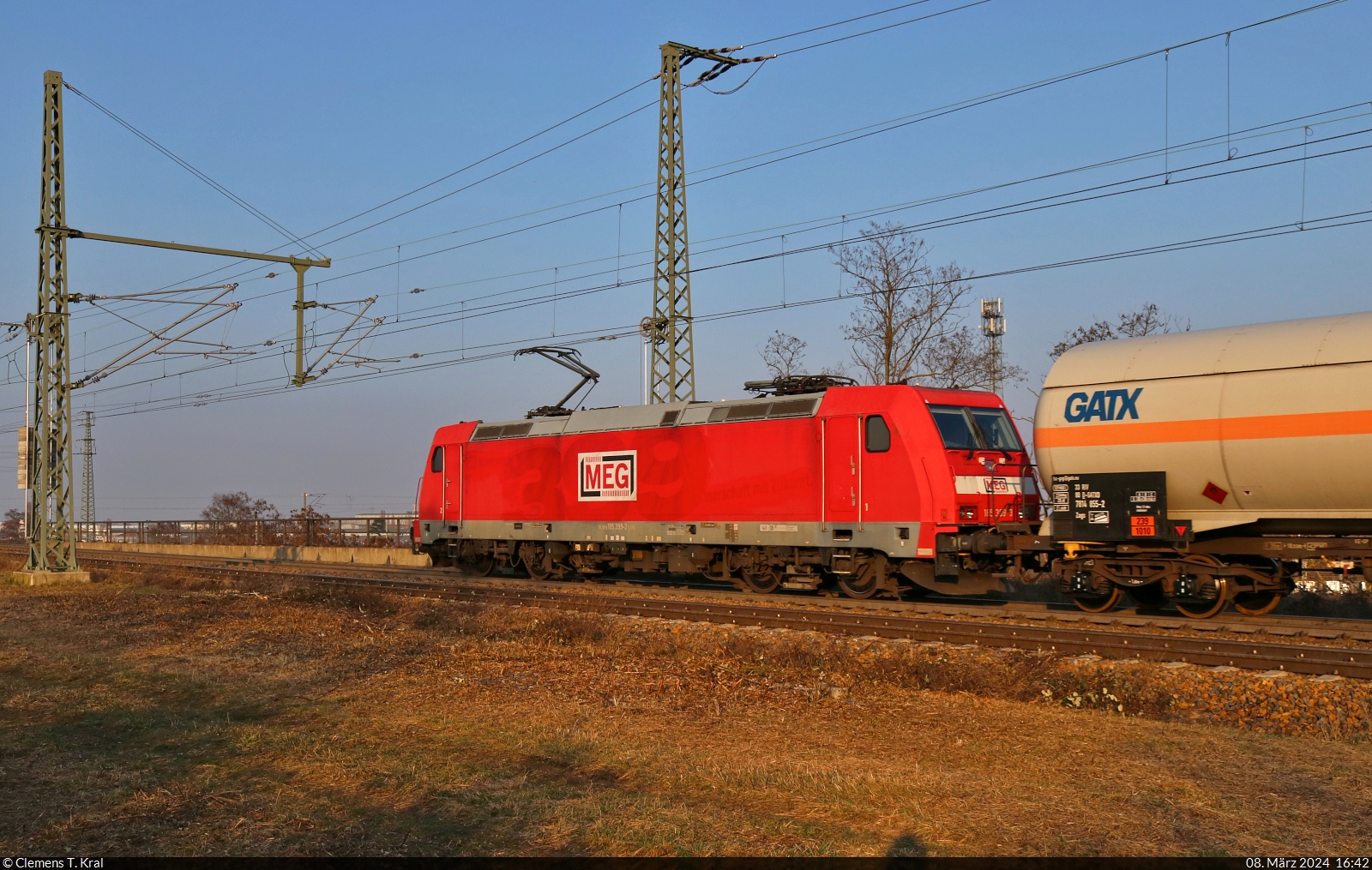 Bombardiers 399. gebaute TRAXX, 185 399-3, hatte am späten Nachmittag des Frauentages die Aufgabe, Kesselwagen über die Gütergleise von Halle (Saale) zu führen. Hier befährt sie die Brücke über die Leipziger Chaussee (B 6) Richtung Zugbildungsanlage (ZBA). Die Jubiläumsfolie wurde inzwischen entfernt, ist aber noch schemenhaft erkennbar.

🧰 DB Cargo, vermietet an die Mitteldeutsche Eisenbahn GmbH (MEG)
🕓 8.3.2024 | 16:42 Uhr