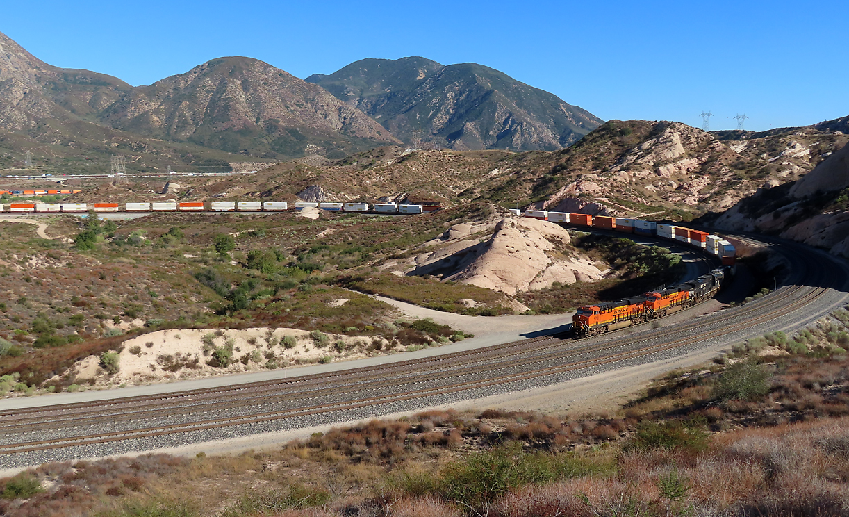 Containerzug auf der Bergfahrt zum Cajon Pass auf der BNSF-Linie in der Sullivan's Curve. Die Wagen links im Hintergrund gehören zum gleichen Zug. Rechts und vorne ist die UP-Doppelspur zu sehen. Cajon Pass, CA, 22.9.2022
