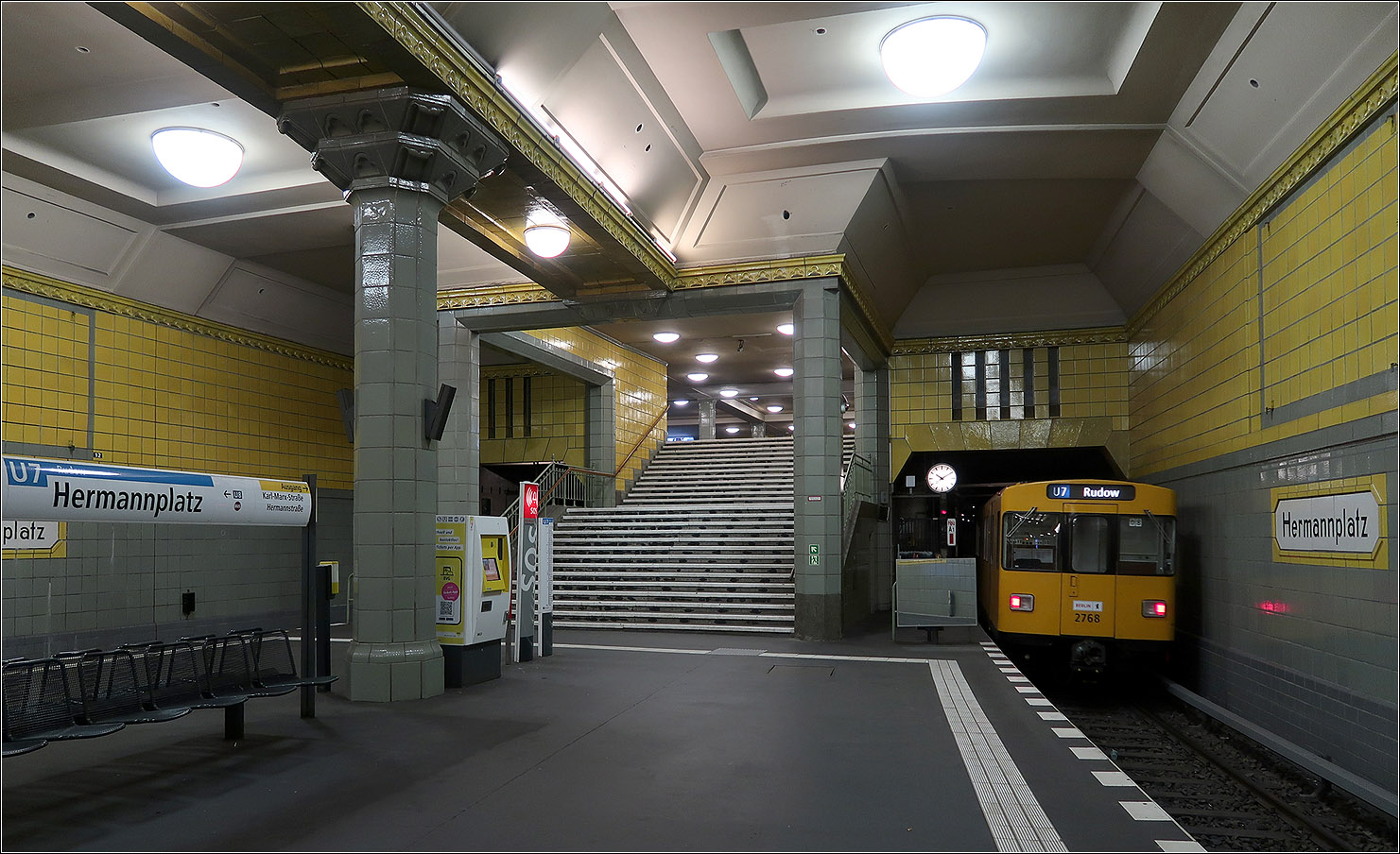 Da wo sich die U7 und U8 kreuzen - 

Blick zum östlichen Ausgang des U-Bahnhofes Hermmanplatz in Berlin-Neukölln. Die Treppen führen durch ein Art Portalbauwerk. Der Bahnhof wurde vom Architekt Grenander reichlich verziert. Mir persönlich würde eine sachlicher Gestaltung besser gefallen, aber es passt gestalterisch in die Entstehungszeit der Anlage.

Der U7-Bahnsteig ist mit 140 Meter Länge länger als sonst üblich in Berlin.

15.07.2023 (M)