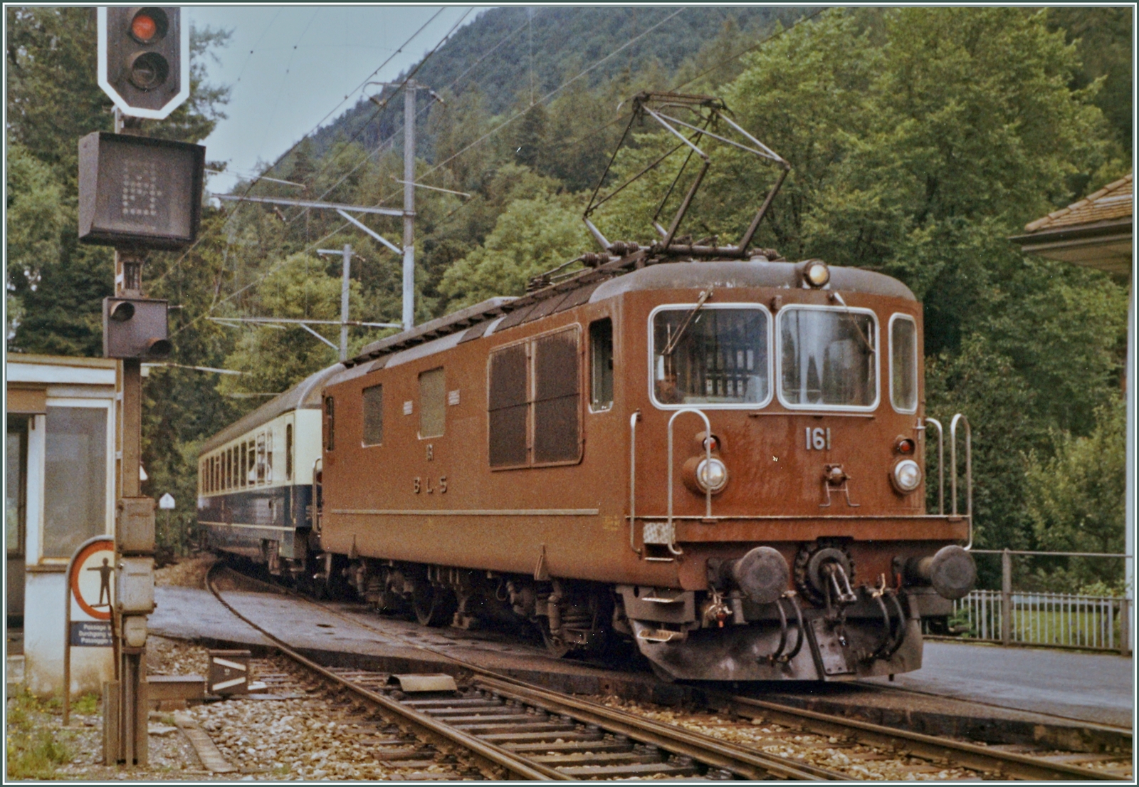 Damit hat es angefangen: 1964 erhielt die BLS die Ae 4/4 II 261 und eine weitere Probemaschine, im Anschluss 1967 drei weitere Loks (Ae 4/4 II 263-265). 1969 wurde die Geschwindigkeit der Ae 4/4 II von 125 km/h auf 140 km/h erhöht und nach eingehenden Probefahrten die Lok zur Re 4/4 161 - 165  umbenannt und war somit von der Leistung her praktisch der SBB Re 4/4 gleichgestellt, bzw. ihr leicht überlegen. 
Im Gegensatz zur SBB Re 4/4 behielt die BLS Re 4/4 während ihre ganzen Einsatzzeit die gleiche Lackierung. 

Im Bild die Re 4/4 161 mit einen DB Grossraumwagen (und weiteren nicht zu sehenden Wagen)  als EC  Thunersee  bei der Einfahrt in Interlaken Ost; leider war mir damals noch nicht bewusst, dass ich keine Signale abschneiden sollte. 

Analogbild vom Sommer 1987