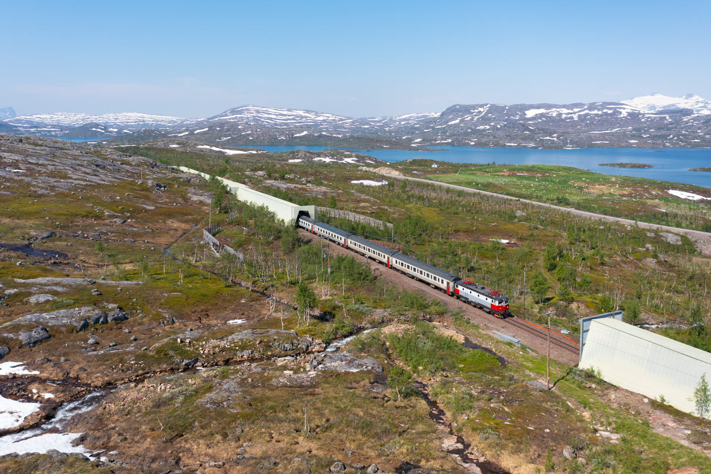 Das letzte Teilstück der Malmbanan/Ofotbanen ab Kiruna bis Narvik ist stark von der rauen Natur im hohen Norden geprägt. Ab Abisko reien sich zahlreiche Lawinenschutzbauten aneinander. Am 28.06.2022 erreicht der IC95 von Narvik nach Luleå in Kürze den Bahnhof Vassijaure. Da am Tag zuvor die Strecke ab dem Nachmittag wegen eines technsischen Defektes gesperrt war, konnte die Nachtzuggarnitur Narvik nicht verlassen und der Tagzug, welcher für den IC95 vorgesehen war, konnte Narvik nicht erreichen. So hat dann am 28.06 die Nachtzuggarnitur den IC95 übernommen.