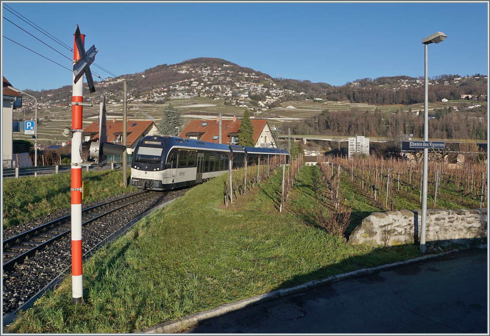 Der CEV MVR ABeh 2/6 7506 von Vevey nach Les Pléiades hat die neue Station  Vevey Vignerons  verlassen und wird in Kürze den namensgebenden Chemin des Vignerons überqueren. 

7. Januar 2023