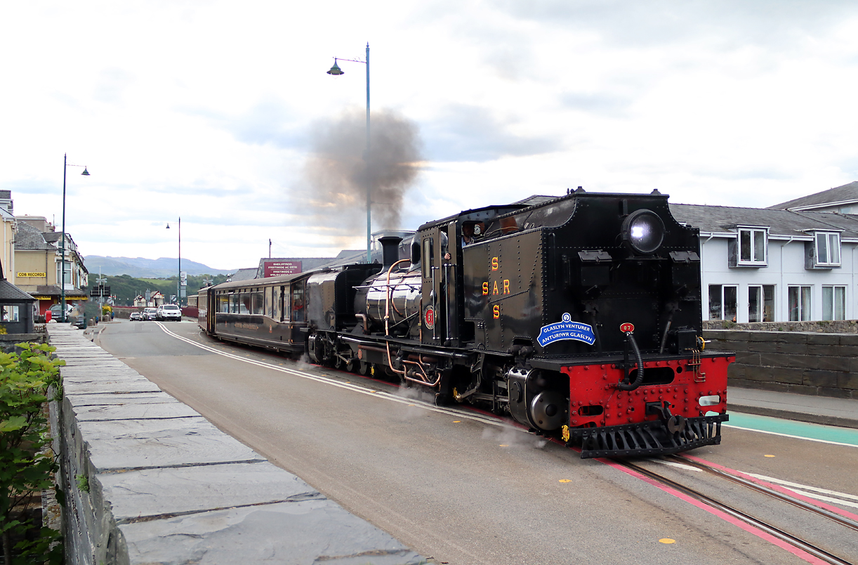 Der Dampfzug von Caernarfon überquert die Strasse und fährt dann in den Bahnhof in Porthmadog ein. Porthmadog, 15.5.2022