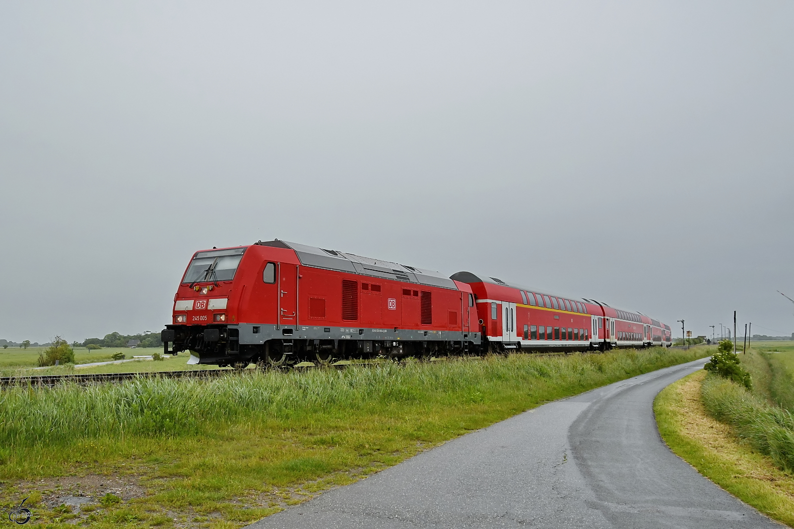 Der von der Diesellokomotive 245 005 gezogene RE6 macht sich nach einem kurzen Stop weiter auf den Weg nach Westerland. (bei Niebüll, Juni 2024)
