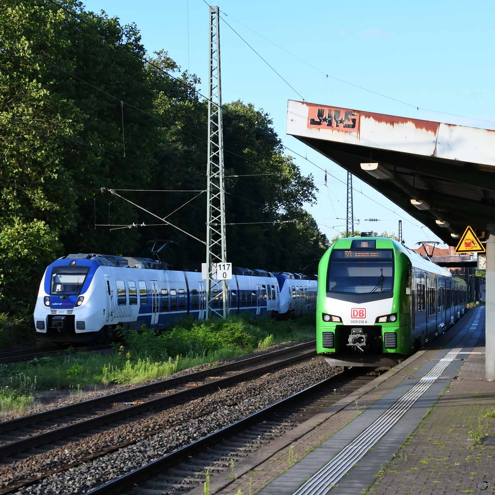 Der Elektrotriebzug 3429 018 kommt gerade in Wuppertal-Unterbarmen an und wird auf dem Ferngleis vom Elektrotriebzug 657 überholt. (August 2023)