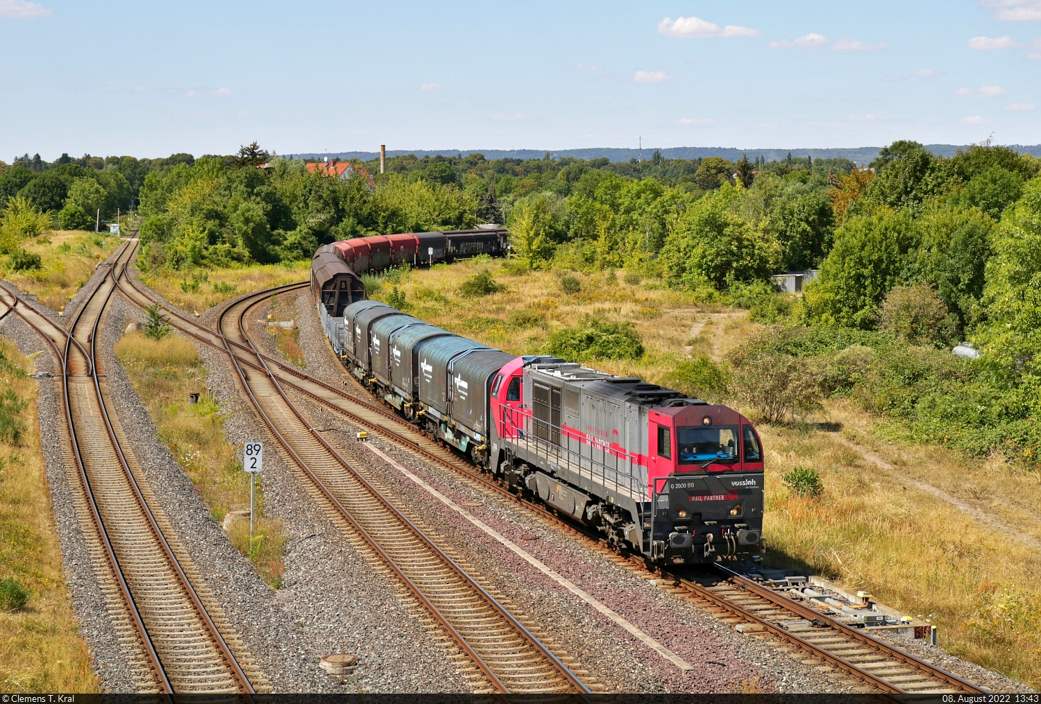Der normalerweise am frühen Morgen verkehrende Aluminiumzug zum Novelis-Werk in Nachterstedt wies eine beträchtliche Verspätung auf. Das hatte auch infrastrukturelle Gründe: Zum einen konnte wegen Schwellenproblemen nicht über Sangerhausen gefahren werden, wie es seit dem 1.7.2022 eigentlich vorgesehen ist, zum anderen war ebenfalls die Strecke zwischen Köthen und Baalberge wegen Bauarbeiten dicht.
Stattdessen nahm der Zug die Route über Magdeburg und Oschersleben(Bode). Als er mit 273 107-3 (Lok 2104 | Vossloh G 2000 BB) an der Spitze in den Bahnhof Halberstadt einfährt, wurde von der Wehrstedter Brücke auf den Auslöser gedrückt.

🧰 Alpha Trains Belgium NV/SA, vermietet an HappyTrain Fleet Services B.V. (HTFS), im Einsatz für Independent Rail Partner B.V. (IRP)/Lineas Group nv/sa
🕓 8.8.2022 | 13:43 Uhr