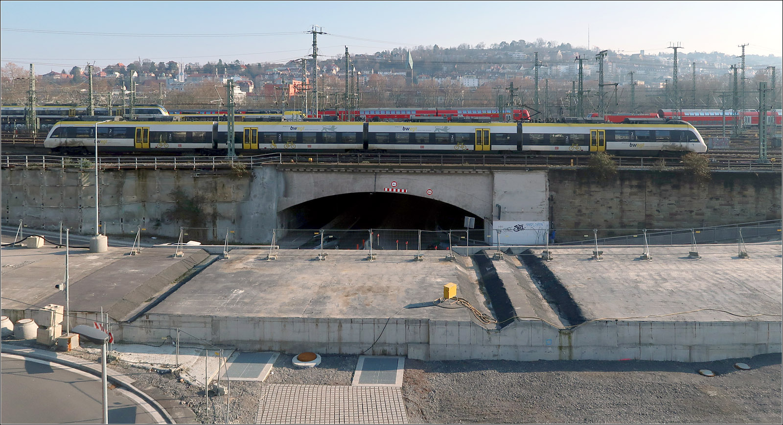 Der S-Bahntunnel blockiert eine Hauptverkehrstraße - 

Der verlängerte S-Bahn-Stammstreckentunnel blockiert die Wolframstraße. Diese unterfährt das Vorfeld des Stuttgarter Hauptbahnhofes und stößt dann auf der Nordwestseite am Ende des Tunnel auf den aus der jetzigen Geländeebene herausragenden rechtwinklig kreuzenden S-Bahntunnel. Da die Straßenfahrbahnen aufgrund der Unterführung zu tief liegen um den Tunnel direkt zu überfahren wurden getrennt für beide Fahrtrichtungen Schlaufen mit Rampen gebaut, die den Tunnel rechts und links überqueren.

09.02.2023 (M)
