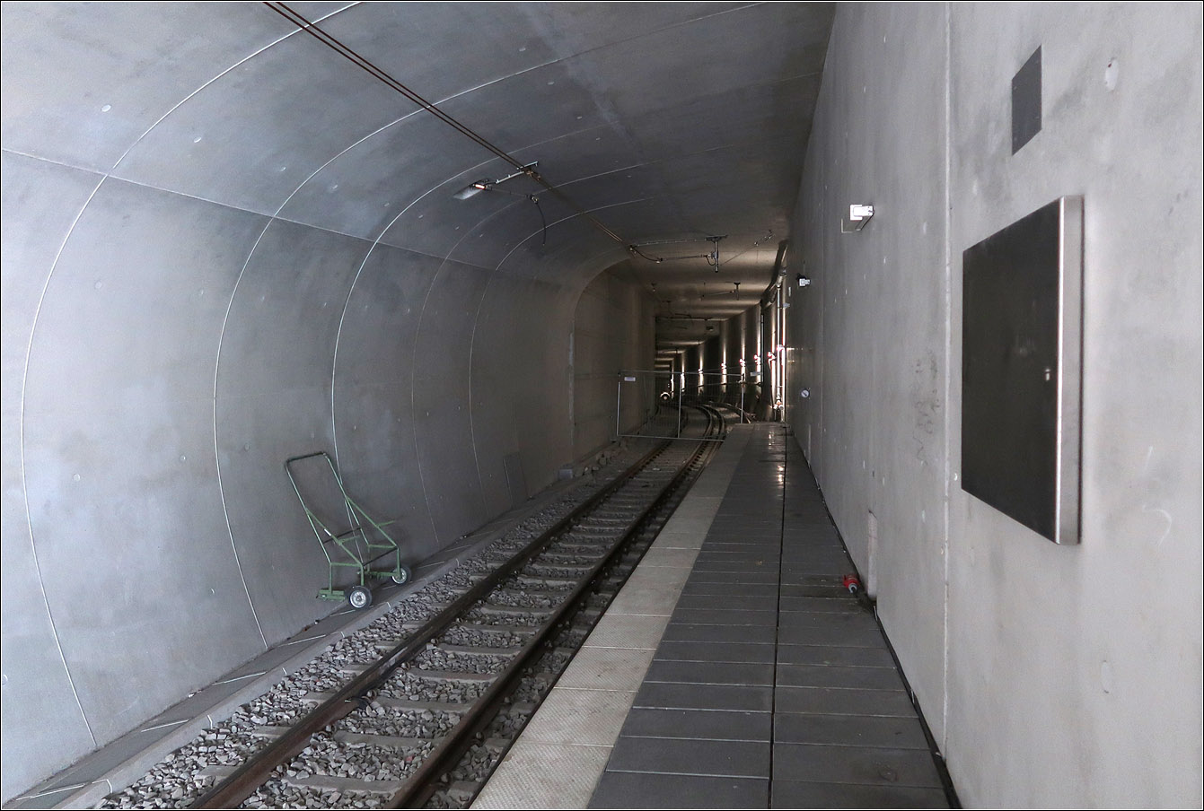 Der vorläufig? letzte Tunnelbau - 

... bei der Stadtbahn Stuttgart ist der Ersatzneubau des Tunnels zwischen Schillerstraße und Staatsgalerie. Der neue Stuttgarter Hauptbahnhof bedingte den Abriss und Neubau der Haltestelle Staatsgalerie mit den Anschluss-Tunnelstrecken. Nachdem man ursprünglich geplant hatte dies weitgehend unter Beibehaltung des Stadtbahnbetriebs zu realisieren mit nur kurzen Sperrungen, änderte man dann doch die Planung und sperrte Teilabschnitte.
Die Rohbauarbeiten am Anschluss der neuen Anlagen an den Tunnel in Richtung Charlottenplatz erfolgte zwischen Mai 2016 und Dezember 2017. Dabei wurde die Verbindung Staatsgalerie - Charlottenplatz gekappt und das Stadtbahnliniennetz entsprechend angepasst.
Im Anschluss daran erfolgte die Stilllegung des Tunnelabschnittes Staatsgalerie - Hauptbahnhof (Arunlf-Klett-Platz) um hier den kreuzungsfreien Abzweig neu bauen zu können. Dies Sperrung wird noch bis zum Dezember 2023 andauern und dauerte dann also über einen Zeitraum von sechs Jahren. Ein Teil der neuen Tunnelstrecken konnte erst nach Abbruch des alten U-Bahnhofes Staatsgalerie erstellt werden, also nach 2020 als die Stadtbahnen in die neue Haltestelle verlegt waren.
Der Tunnelanschluss in Richtung Neckartor wurde dabei unter laufendem Betrieb gebaut, mit nur kurzer Sperrung.

Das Bild zeigt an der Station Staatsgalerie das vom Hauptbbahnhof (Arnulf-Klett-Platz) kommende Gleis, das die Streckengleise Richtung Charlottenplatz kreuzungsfrei unterfährt. Ein Teil des alten Tunnels wird übrigens für eine Abstellanlage genutzt werden.

Nachdem es seit beginn des Stadtbahnbaus in Stuttgart 1962 (zuerst U-Straßenbahn, dann U-Bahn, dann Stadtbahn) durchgehend immer Tunnelprojekte gegeben hat, wird nach Fertigstellung dieser Tunnelstrecke in absehbarer Zeit keine weiteren Tunnelbaustellen für die Stadtbahn mehr geben.

21.07.2023 (M)