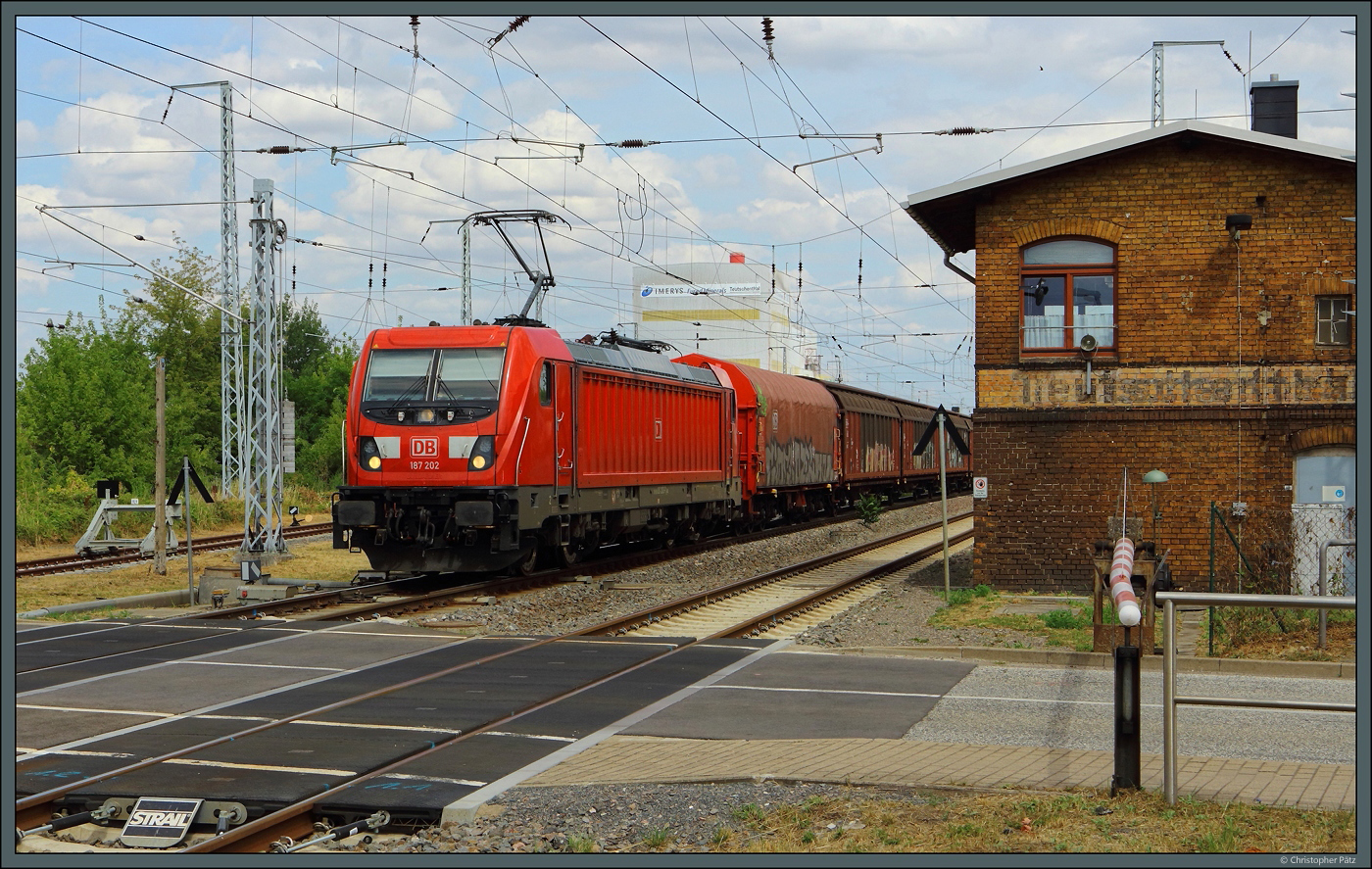 Der westlichen Bahnhofskopf von Teutschenthal wird vom elektromechanischen Stellwerk W2 bedient. Am 14.07.2023 passiert 187 202 der DB Cargo mit einem Güterzug das Stellwerk und den Bahnübergang mit mechanischer Vollschranke.