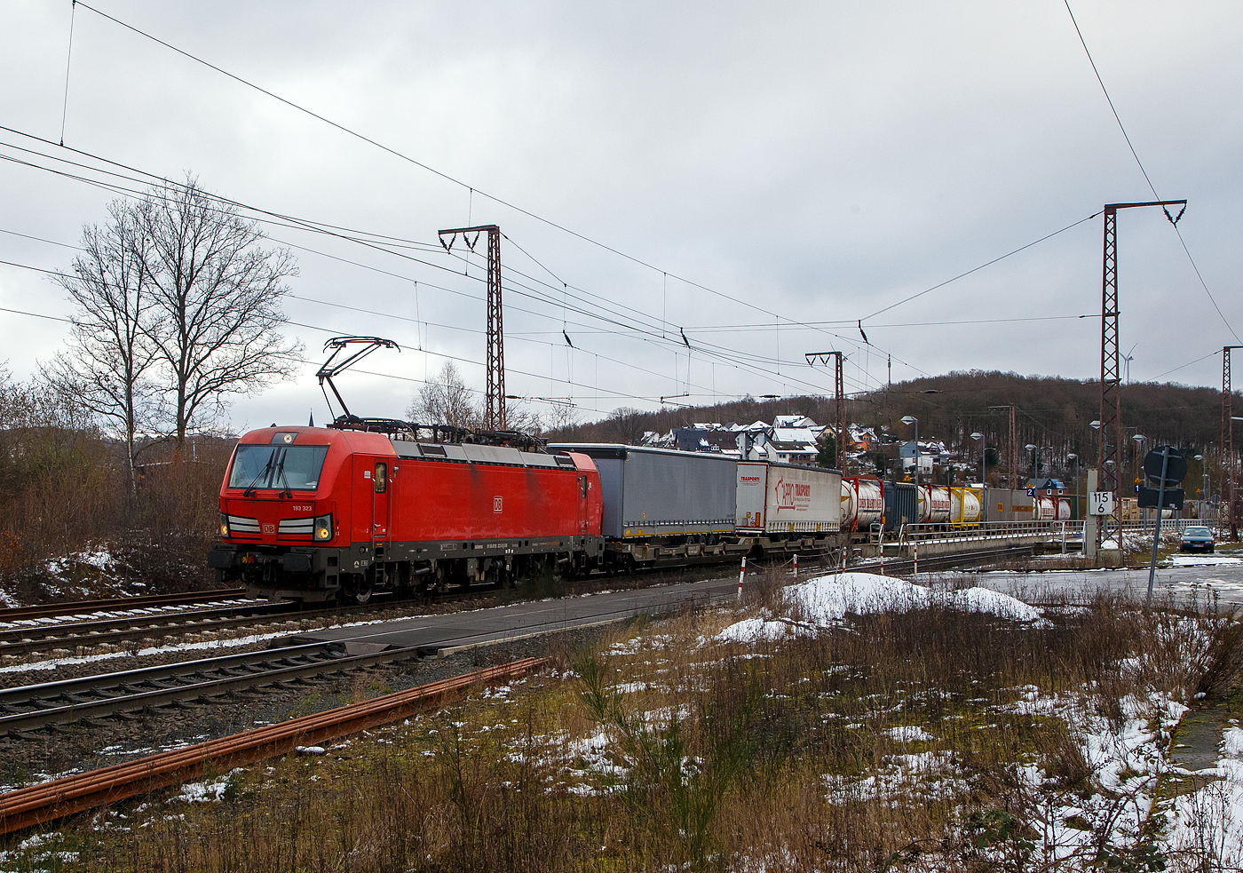 Die 193 323-3 (91 80 6193 323-3 D-DB) der DB Cargo AG fährt am 27.01.2023 mit einem „HUPAC“ KLV-Zug durch Rudersdorf (Kr. Siegen) in Richtung Siegen. Hier befährt der Zug die Dillstrecke (KBS 445) von dieser geht es bei Siegen-Ost auf die Siegstrecke (KBS 460) in Richtung Köln. Weil die Ruhr-Sieg-Strecke (KBS 440) nicht das KV-Profil P/C 400 aufweist, sind solche Züge dort nur bis Kreuztal zum Südwestfalen Container-Terminal möglich.

Die Siemens Vectron MS (200 km/h - 6.4 MW) wurden 2018 von Siemens unter der Fabriknummer 22448 und gebaut, sie hat die Zulassungen für Deutschland, Österreich, Schweiz, Italien und die Niederlande (D/A/CH/I/NL).