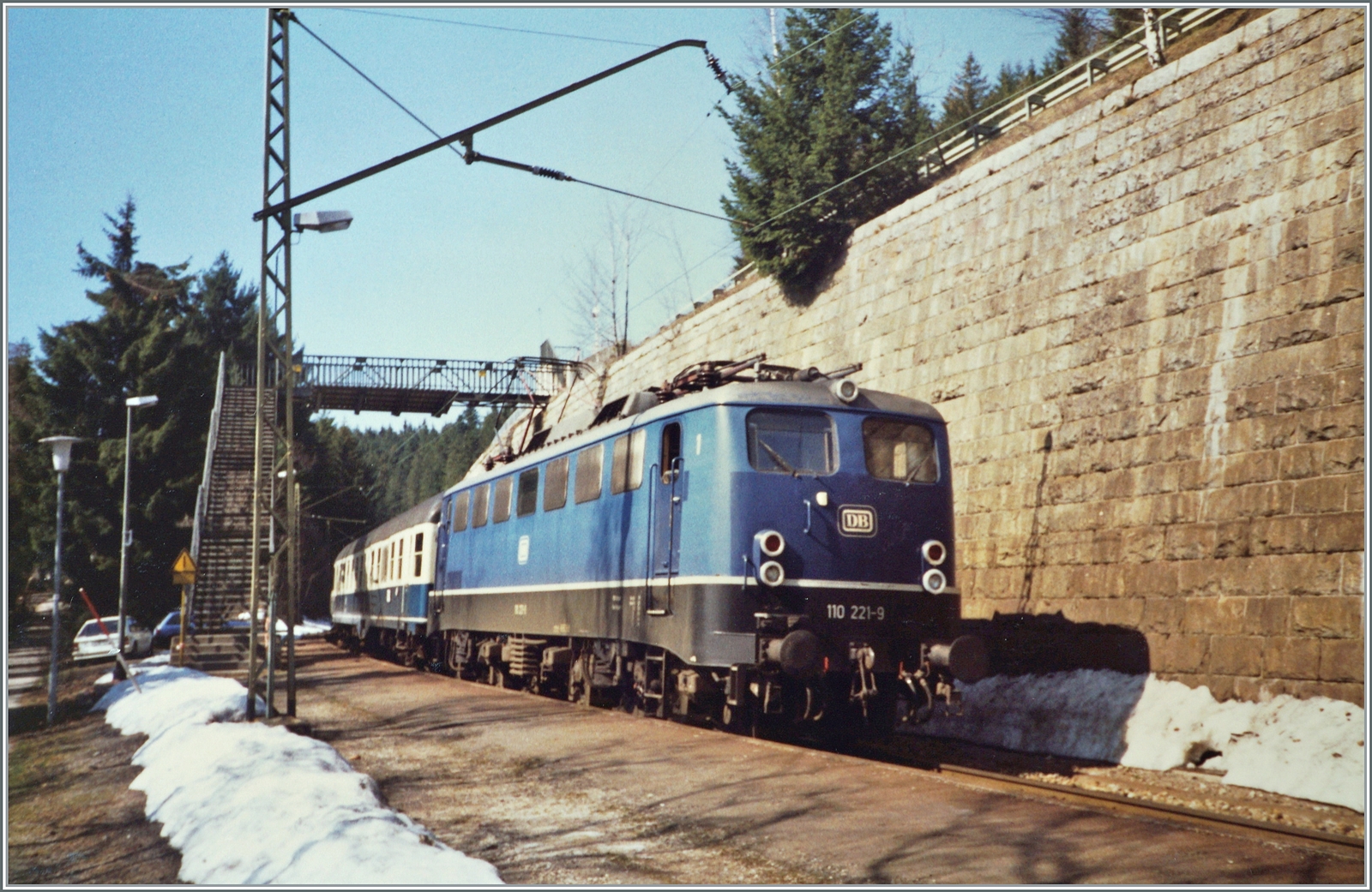 Die DB 110 221-9 erreicht mit ihrem FD 703 von Münter (Westfallen) kommend den Zielbahnhof Seebrugg. 
Der FD 703  Bodensee verkehrte von Münster (ab 7:06) nach Konstanz (an 15:55) führte neben den vier Bm einen Speisewagen WRbumz einen klimatisierten 1. Klassenwagen Avm. Kurzwagen gruppen fuhren nach Lindau, Basel und wie hier im Bild nach Seebrugg.

Analogbild vom April 1988 