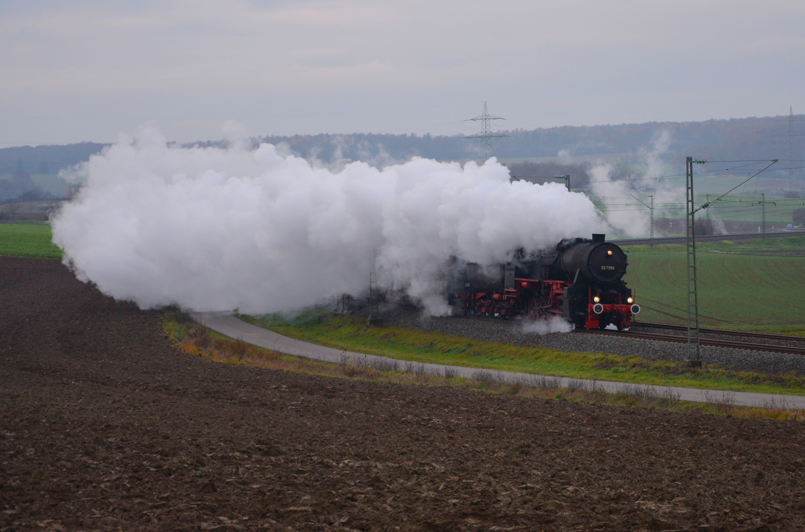 Die Eisenbahnfreunde Zollernbahn (EFZ) überführten am 09.12.2022 ihre Dampflokomotiven 52 7596 und 01 519, die sich in der Dampfschwade versteckt, von Rottweil nach Mellrichstadt. Hier in einer langgezogenen Kurve auf der Frankenbahn bei Moos.
