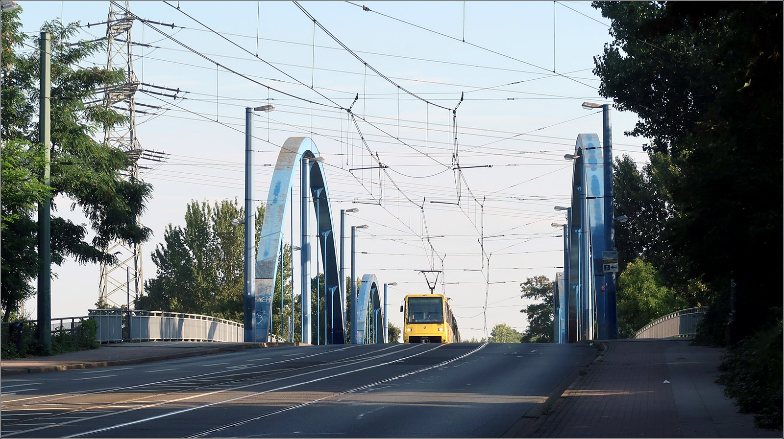 Die Nordstrecke der Essener Stadtbahn - 

Der Rhein-Herne-Kanal wird von der Stadtbahnlinie U11 auf einer Bogenbrücke überquert. Die Gleise liegen im Straßenraum.
Man beachte auch die an seitlichen Masten aufgehängte Hochkettenfahrleitung. Zusammen mit den drüber liegenden Hochspannungsleitungen ergibt sich ein faszinierendes Netz aus Leitungen.

22.03.2023 (M)