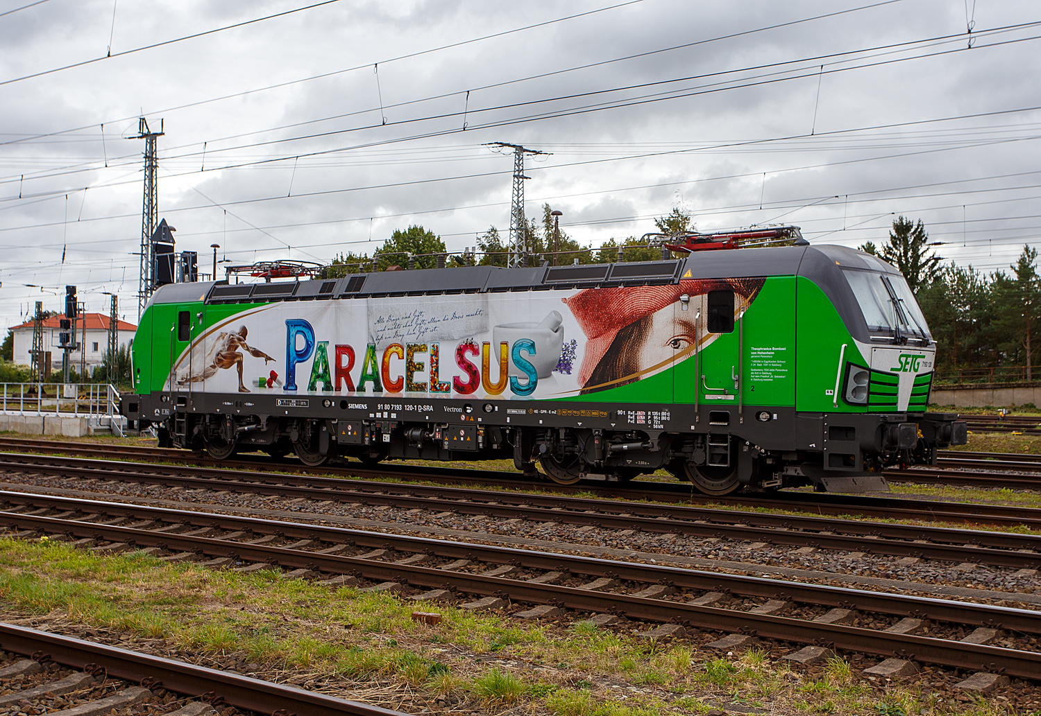 Die recht neue SIEMENS Vectron AC DPM 7193 120 (91 80 7193 120-1 D-D-SRA) „Parcelsus“ der SETG - Salzburger Eisenbahn TransportLogistik GmbH ist am 24 September 2026 beim Stendal Hauptbahnhof abgestellt. 

Kurz zum Namen der Lok „Parcelsus“:Theophrastus Bombast von Hohenheim, genannt Paracelsus (* 1493 oder 1494 in Egg in der N�he von Einsiedeln, Kanton Schwyz; † 24. September 1541 in Salzburg). Sp�testens 1524 lebte Paracelsus als Arzt in Salzburg. 

Die SIEMENS Vectron AC DPM der Variante B14 mit Diesel Power Modul bzw. mit LM (Last Mile Diesel) wurde 2026 von Siemens Mobilitiy in M�nchen-Allach unter der Fabriknummer 24042 gebaut. Diese Vectron Lokomotive ist als AC DPM – Lokomotive (Wechselstrom-Variante mit Dieselmodul f�r Rangieren ohne Fahrdraht) mit 6.400 kW konzipiert, im Dieselbetrieb betr�gt die Leistung lediglich 180 kW (160 kW am Rad). In der VECTRON Variante AC B14 hat sie die Zulassungen f�r Deutschland, �sterreich, Ungarn, Tschechien, Slowakei, Rum�nien und Bulgarien (D / A / H / CZ / SK / RO / BG). So besitzt die Variante AC B14 folgende Zugsicherungssysteme:
ETCS BaseLine 3, sowie f�r 
Deutschland (PZB90 / LZB80 (CIR-ELKE I))
�sterreich (ETCS Level 1 mit Euroloop, ETCS Level 2, PZB90 / LZB80)
Ungarn (ETCS Level 1, EVM (Mirel))
Tschechien und Slowakei (LS (Mirel))
Rum�nien und Bulgarien (PZB90)

Diese topmodernen Lokomotiven weisen eine Leistung von 6.400 kW (8.700 PS) auf. Das eingebaute Diesel-Power-Modul erm�glicht das Rangieren ohne Fahrdraht. Zus�tzlich sind die Vectron-Lokomotiven von Siemens mit einer Funkfernsteuerung und einer halbautomatischen Bremsprobe ausger�stet. 

Die Entwicklung der Siemens Lokomotive Vectron basiert auf den Erfahrungen der erfolgreichen EuroSprinter beziehungsweise deren Weiterentwicklung Siemens ES 2007 (NMBS/SNCB-Reihe 18/19) ersetzt. Ausgereifte und bew�hrte Technik ist mit Flexibilit�t und Modularit�t kombiniert. Die Vectron Lokomotive ist f�r die vielf�ltigsten Verkehrsaufgaben konzipiert. Ob im nationalen oder grenz�berschreitenden Verkehr, ob im Personen- oder G�terverkehr. Es werden vier elektrische Versionen und eine dieselelektrische Version der Lokomotivplattform angeboten. Die hier gezeigten Vectron Lokomotiven sind als AC – Lokomotiven (Wechselstromlok) mit 6.400 kW Leistung) konzipiert und haben ein Diesel Power Modules (DPM) / Rangiermodul bzw. Last Mile (LM).

Die �u�ere Gestaltung der Vectron-Lokomotiven unterscheidet sich nur wenig von der der Siemens ES 2007; insbesondere wird das der Crashnorm entsprechende Kopfmodul bis auf einige Detail�nderungen, etwa R�ckblickkamera statt Seitenfenster, �bernommen. Innen ist der neue Typ hingegen komplett anders aufgebaut. Der Maschinenraum besitzt im Gegensatz zur Bombardier TRAXX einen geraden Mittelgang, an dessen Seiten alle Komponenten einen festen Platz haben. In einem unter dem Boden verlaufenden Kanal verlaufen die Steuerleitungen und Druckluftrohre. Die Rads�tze werden �ber gefederte Ritzel-Hohlwellen angetrieben.

Der Vectron unterst�tzt mit einer optimierten Systemauslegung und vielf�ltigen Funktionen f�r energieoptimales Abstellen. Der elektrische Vectron erm�glicht eine erh�hte elektrische Bremskraft von 240 kN. Die r�ckgewonnene Energie wird hocheffizient f�r die Versorgung von Hilfsbetrieben genutzt bzw. und wo m�glich ins Netz zur�ckgespeist.

TECHNISCHE DATEN der Vectron AC DPM:
Spurweite: 1.435 mm (Normalspur)
Achsformel: Bo'Bo'
L�nge �ber Puffer: 18.980 mm
Drehzapfenabstand: 9.500 mm
Achsabstand im Drehgestell: 3.000 mm
Breite: 3.012 mm
H�he: 4.248 mm
Raddurchmesser: 1.250 mm (neu) / 1.160 mm (abgenutzt)
Gewicht: 90 t
Spannungssysteme: 15 kV, 16,7 Hz AC (Wechselstrom)
Max. Leistung am Rad: 6.400 kW
Leistungsfaktor: nahe 1
H�chstgeschwindigkeit: 160 km/h
Anfahrzugskraft: 300 kN
Dauerzugkraft: 250 kN
Elektrische Bremskraft: 240 kN
Kraft�bertragung: Ritzelhohlwellenantrieb
Lichtraumprofil: UIC 505-1

Leistungsdaten DPM (Diesel Power Modul):
Max. Geschwindigkeit: 40 km/h
Leistung: 180 kW (160 kW am Rad)
Tankvolumen der DPM:  350 l (Diesel)
