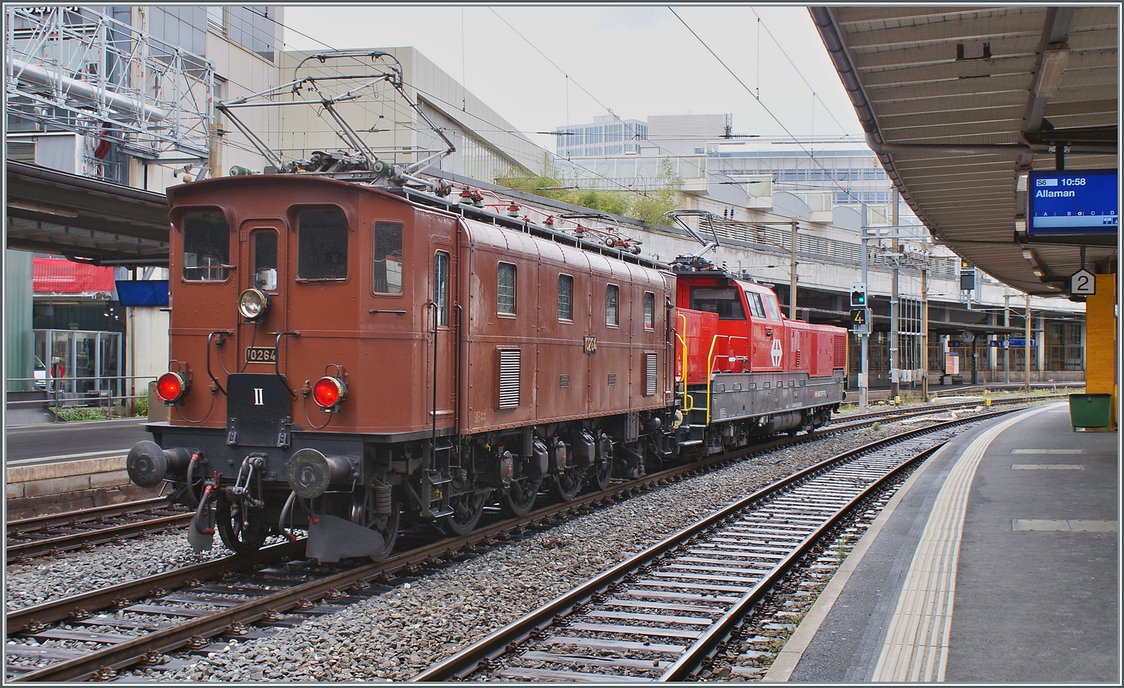Die SBB Historic Ae 3/6 III 10264 schiebt in Lausanne ein mächtiges ETCS Gerät in Form einer Aem 940 vor sich her. Die Lok ist wohl auf der Rückfahrt vom Dépôt Fest in Olten nach St-Maurice. In den Jahren 1925 und 1926 wurden die kleine Serie der elf Ae 3/6 III 10261 - 10271 gebaut, die 89 Tonnen schwere Lok hatte eine Höchstgeschwindigkeit von Km/h 90 und 1800 PS. Die Lok wurde entwickelt, da recht kurzen Ae 3/5 bei hoher Geschwindigkeit schlechte Fahreigenschaften aufwiesen, somit wurde die Konstruktion der Ae 3/5 einfach verlängert und als Ae 3/6 III in Dienst gestellt. Interessanterweise wurden die letzten Ae 3/5 erst 1983 ausrangiert, die letzte Ae 3/6 III 1980.

28. August 2023