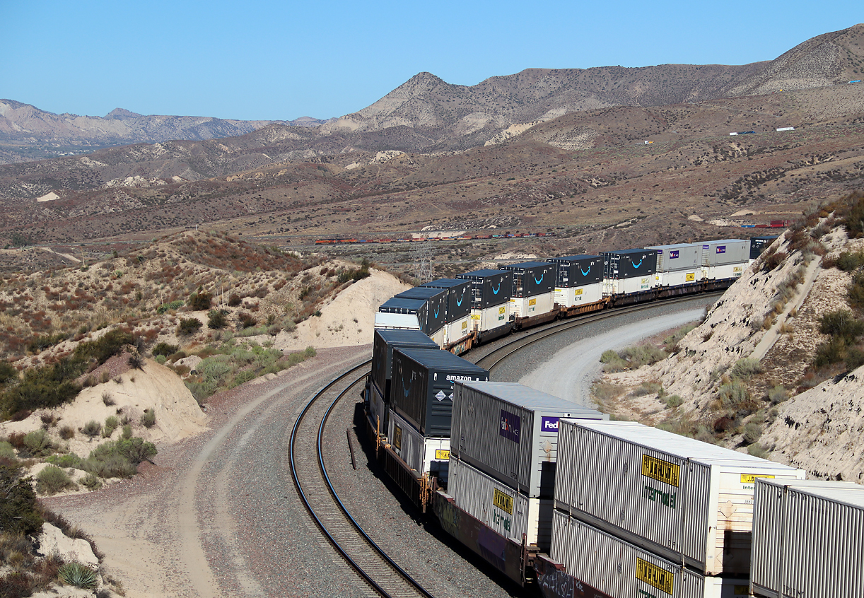 Dieser Containerzug rollt von der Passhöhe talwärts Richtung Fotostelle 'Hill 582' (die kleine Baumgruppe links in der Mitte am Bildrand) und San Bernardino. Cajon Pass, CA, 22.9.2022