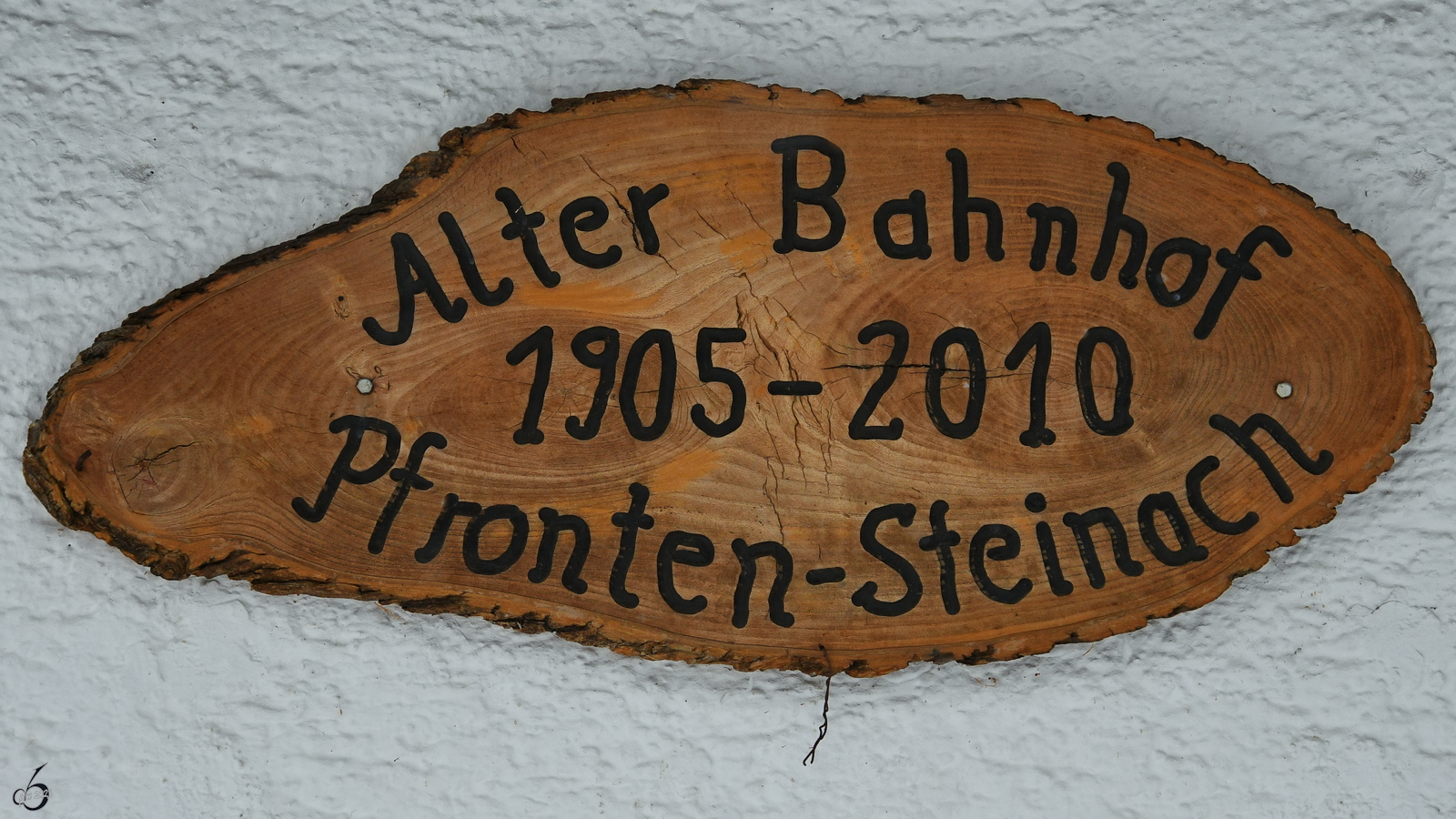 Ein Holzschild weist auf die Historie des Bahnhöfes in Pfronten-Steinach hin. (November 2023)