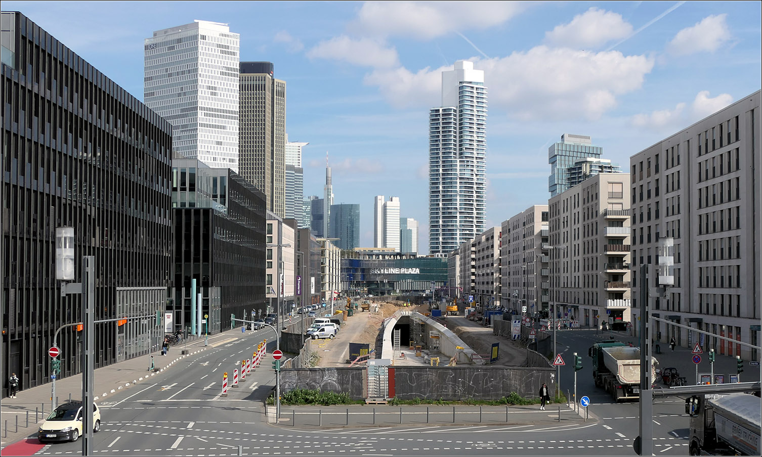Ein neues U-Bahnportal - 

... in Frankfurt. Durch das Europaviertel soll in Zukunft die Linie U5 verkehren. Diese zweigt am Hauptbahnhof von der U4 ab um über die U-Station Güterplatz in der Europa-Allee über eine Rampe die Oberfläche zu erreichen. Von hier geht es oberirdische weiter im breiten Mittelstreifen der Europa-Allee. Der Europagarten wird wie auch der Autoverkehr im Tunnel unterfahren. Dieser Tunnel ist schon erstellt. Die Fertigstellung verzögert sich um zwei Jahre. Eigentlich sollten die Bahnen 2025 fahren, jetzt ist 2027 vorgesehen. Allerdings will man bis dahin die Strecke um zwei weitere Haltestellen bis zum Römerhof verlängern.

Am Fotostandpunkt kreuzt die neue U5-Strecke die S-Bahnstrecke der Linien S3, S4, S5 und S6, aber es wird dort keine Umstieg möglich sein, da ein weitere S-Bahnhof an dieser Stelle zu nahe an den Stationen Galluswarte und Messe liegen würde.

21.03.2024 (M)

